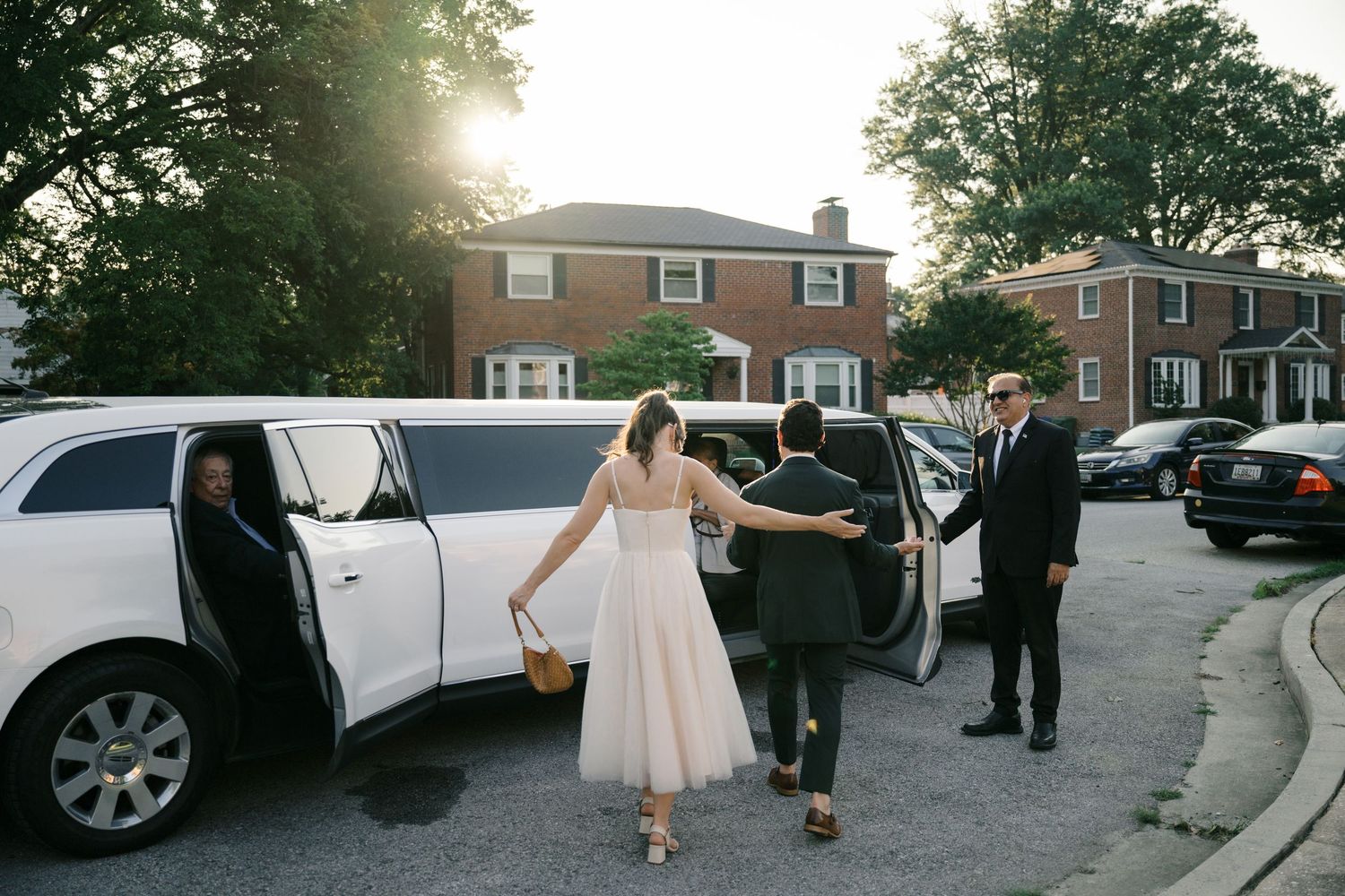 Newlyweds celebrate outside at sunset with their wedding party in a parking lot setting.