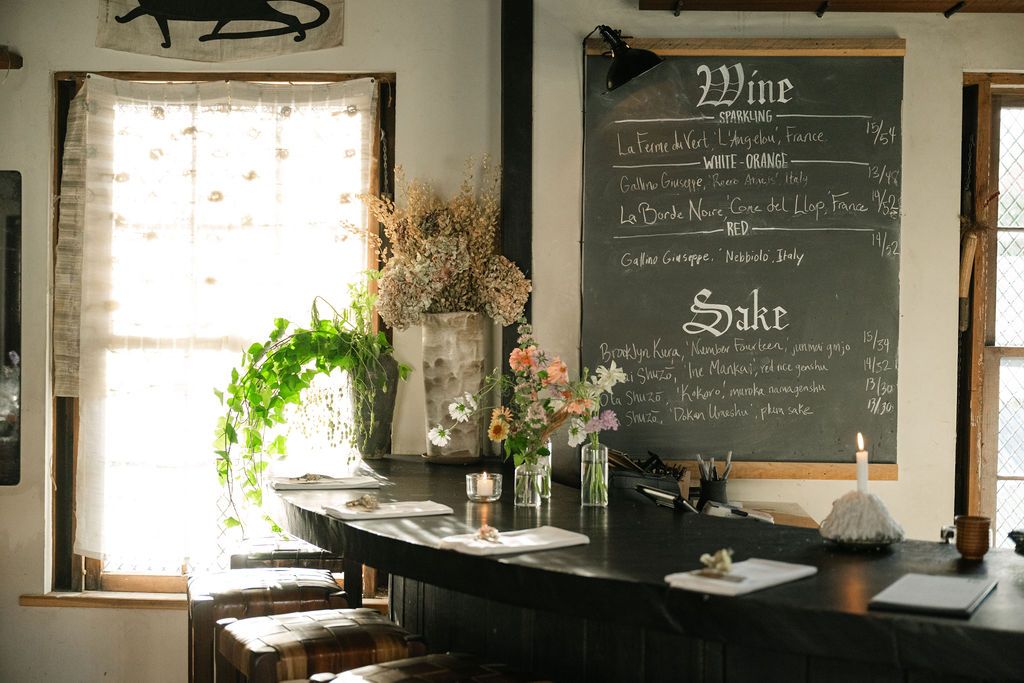 A cozy restaurant interior with chalkboard menu, window light and rustic decor.