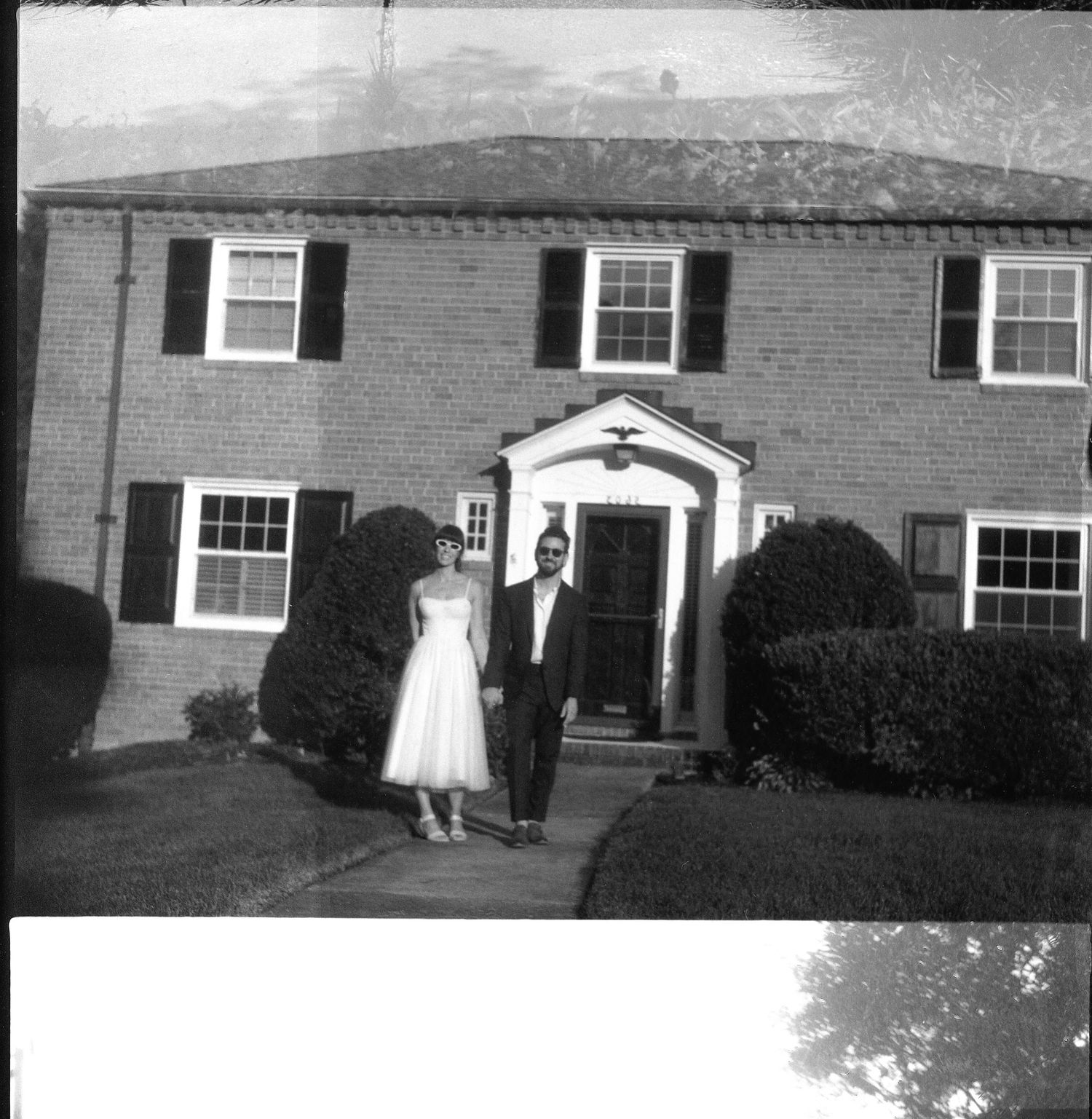 Black and white photo showing a series of suburban ranch-style houses with traditional windows and brick exteriors.