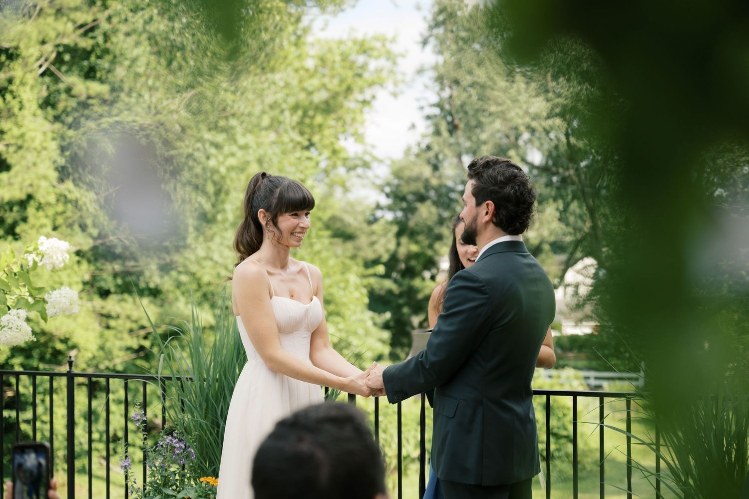 Wedding couple shares tender first look moment in a lush garden setting framed by greenery.