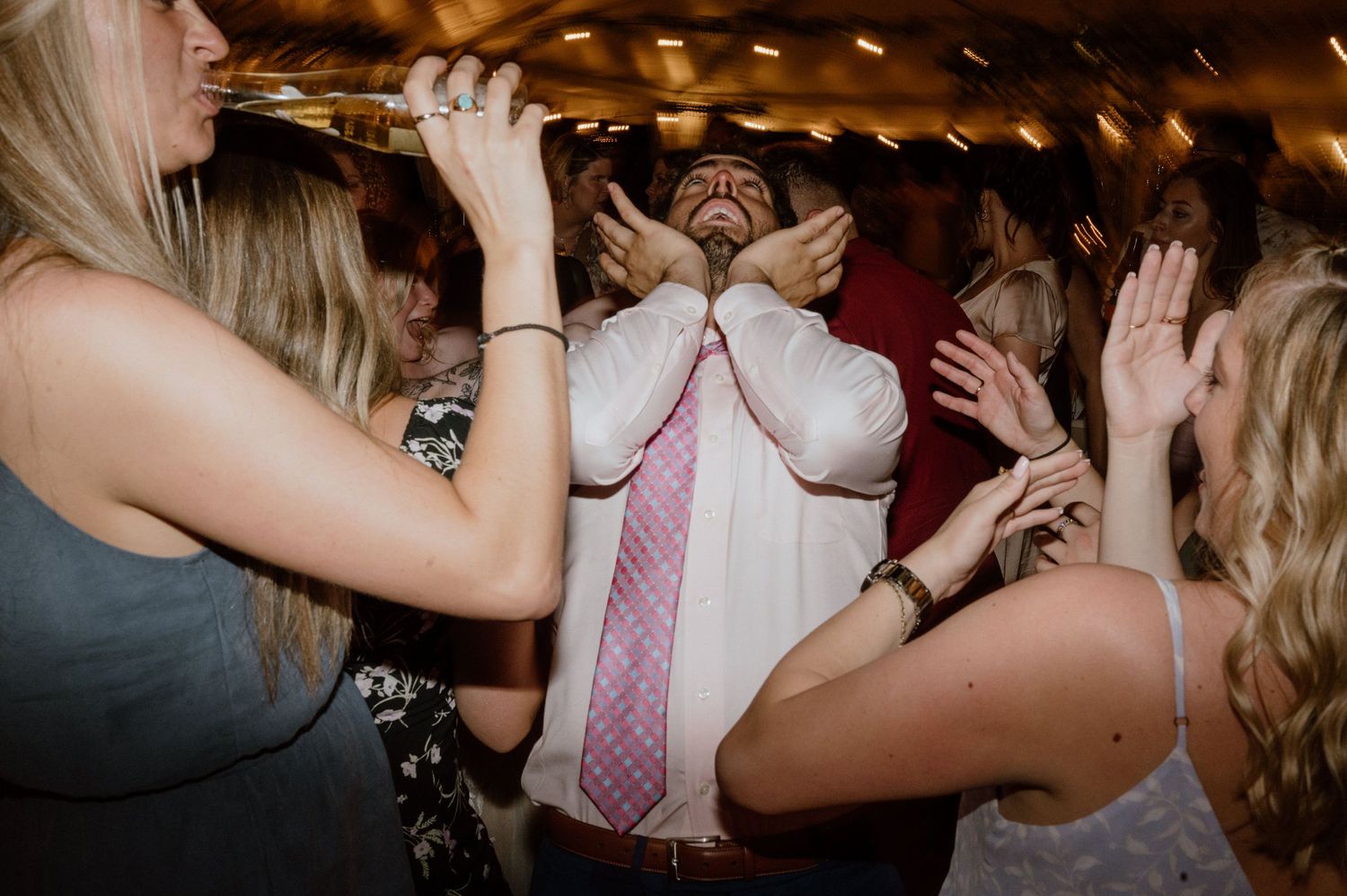 Party guests dancing and singing enthusiastically at a celebratory event.