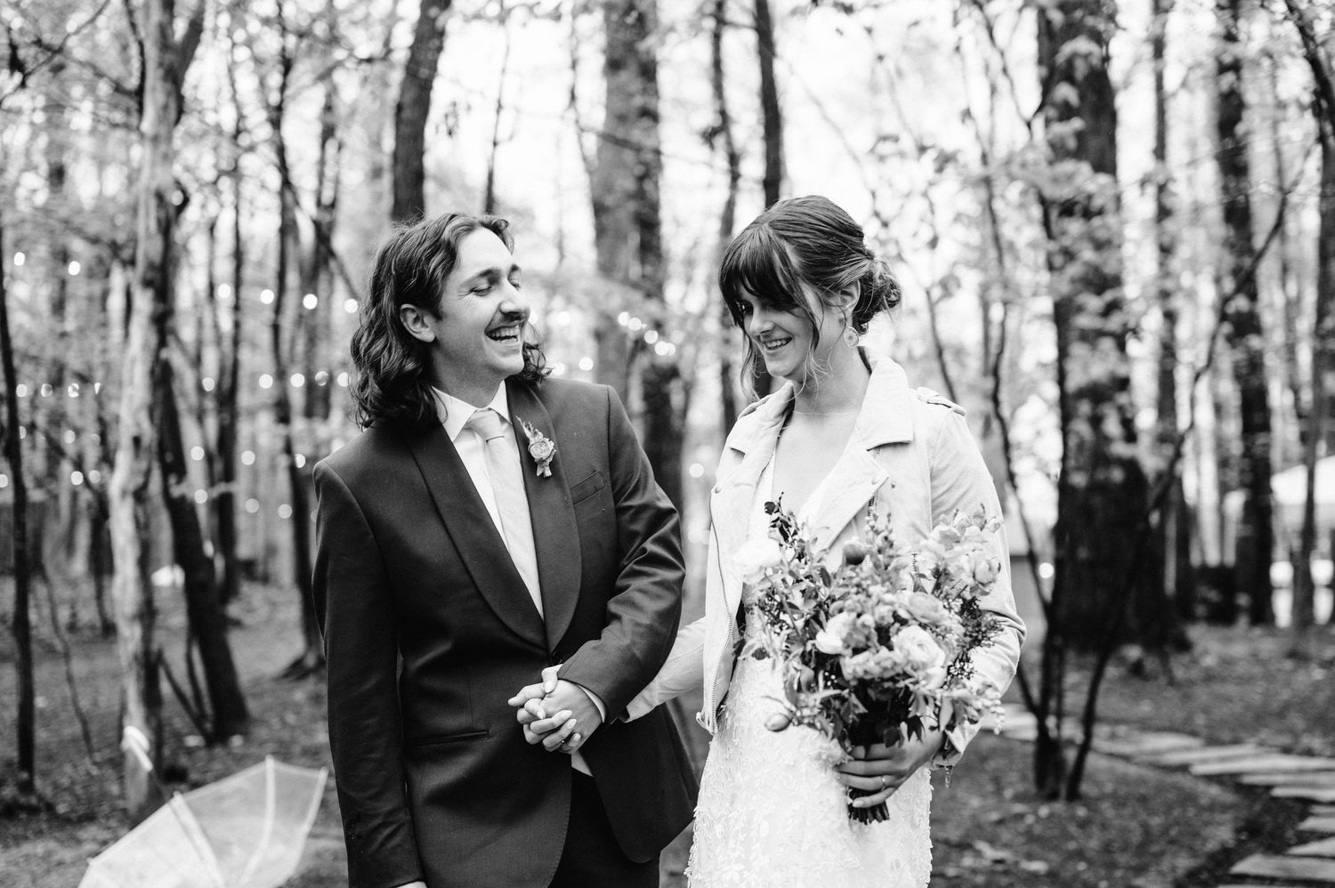 A couple shares a joyful moment in a birch forest on their wedding day.