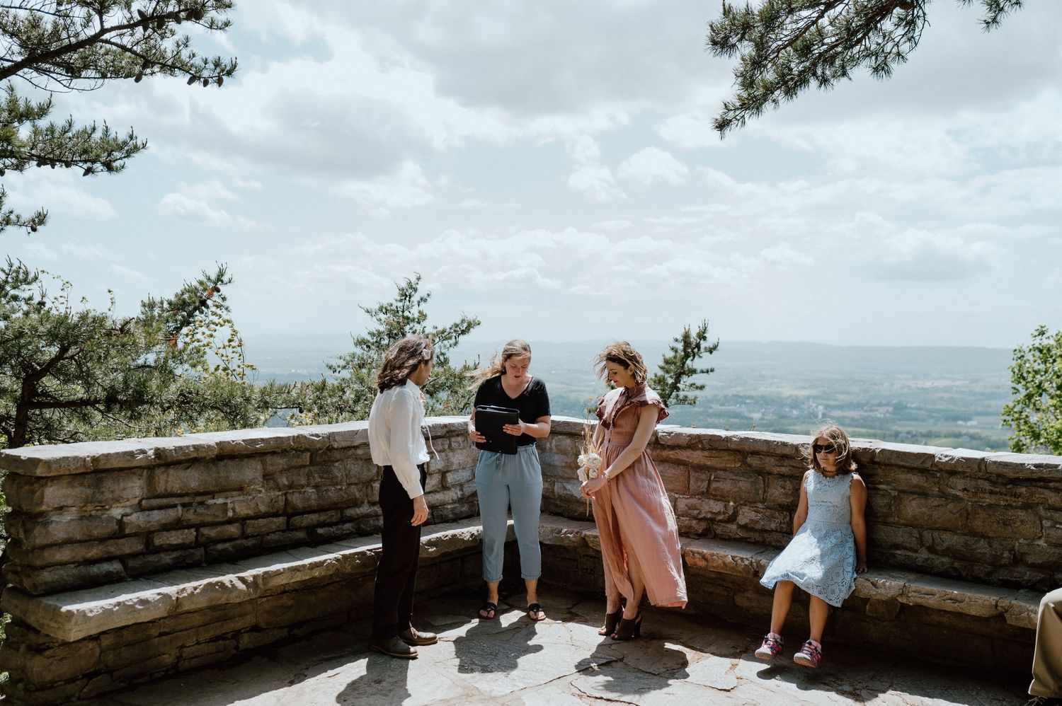 Group gathered at a scenic mountain overlook with stone walls.