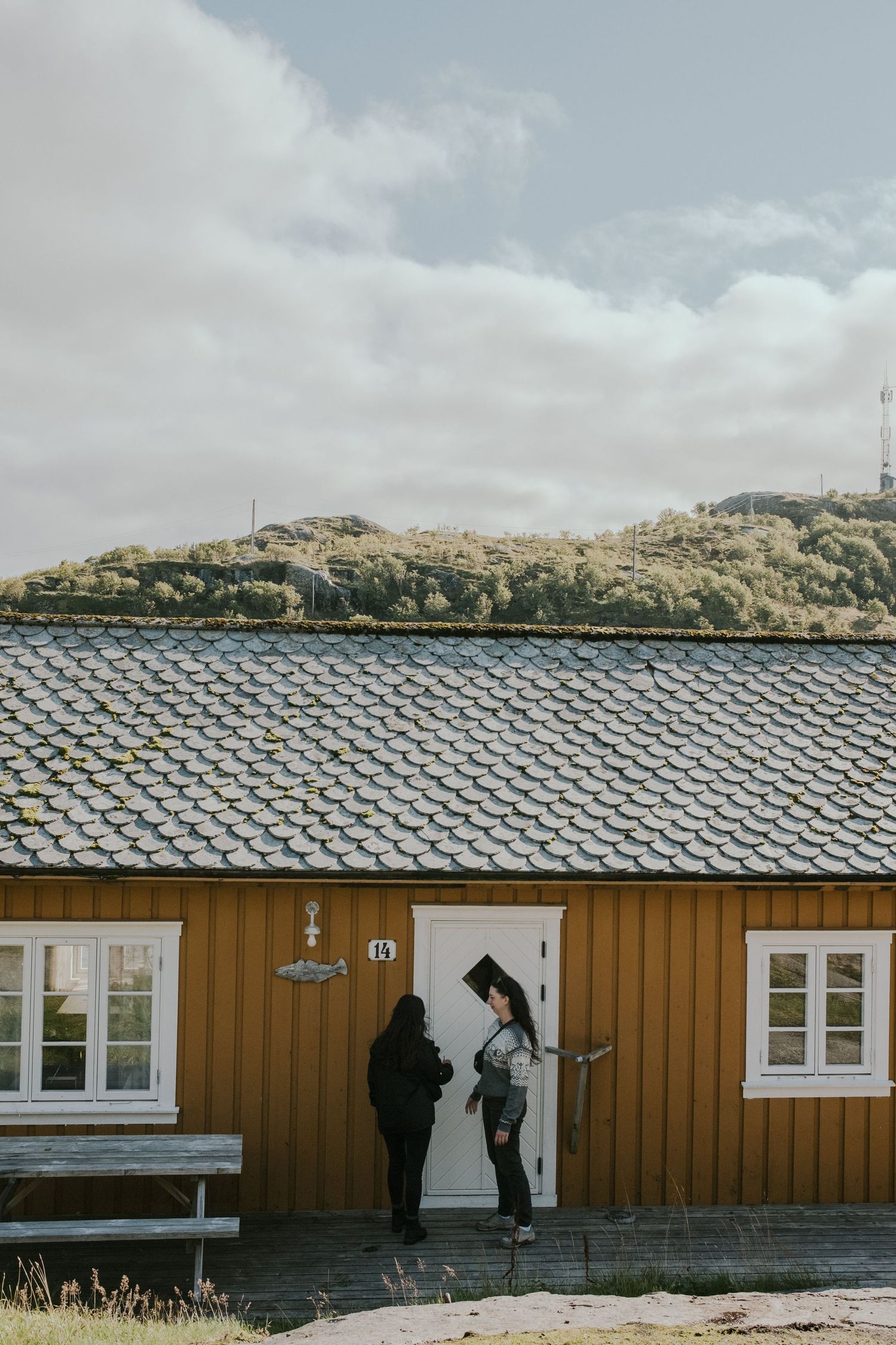 Rustic wooden cabin with traditional slate roof in mountainous Norwegian landscape.