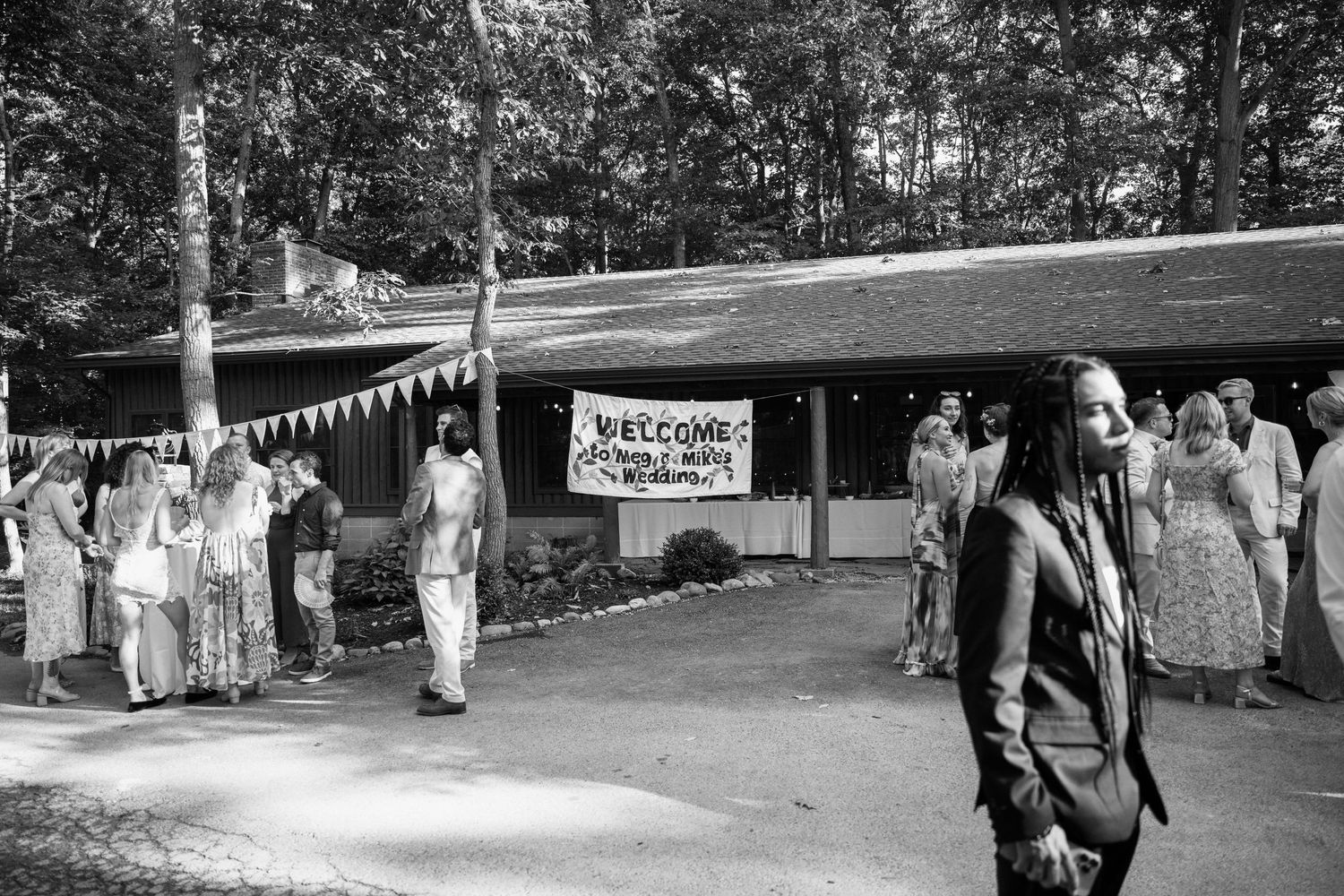 Black and white photo of a vintage camp gathering with bunting decorations and a welcome banner.