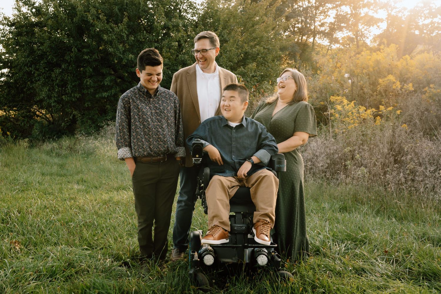 Family portrait in a sunlit meadow during golden hour.