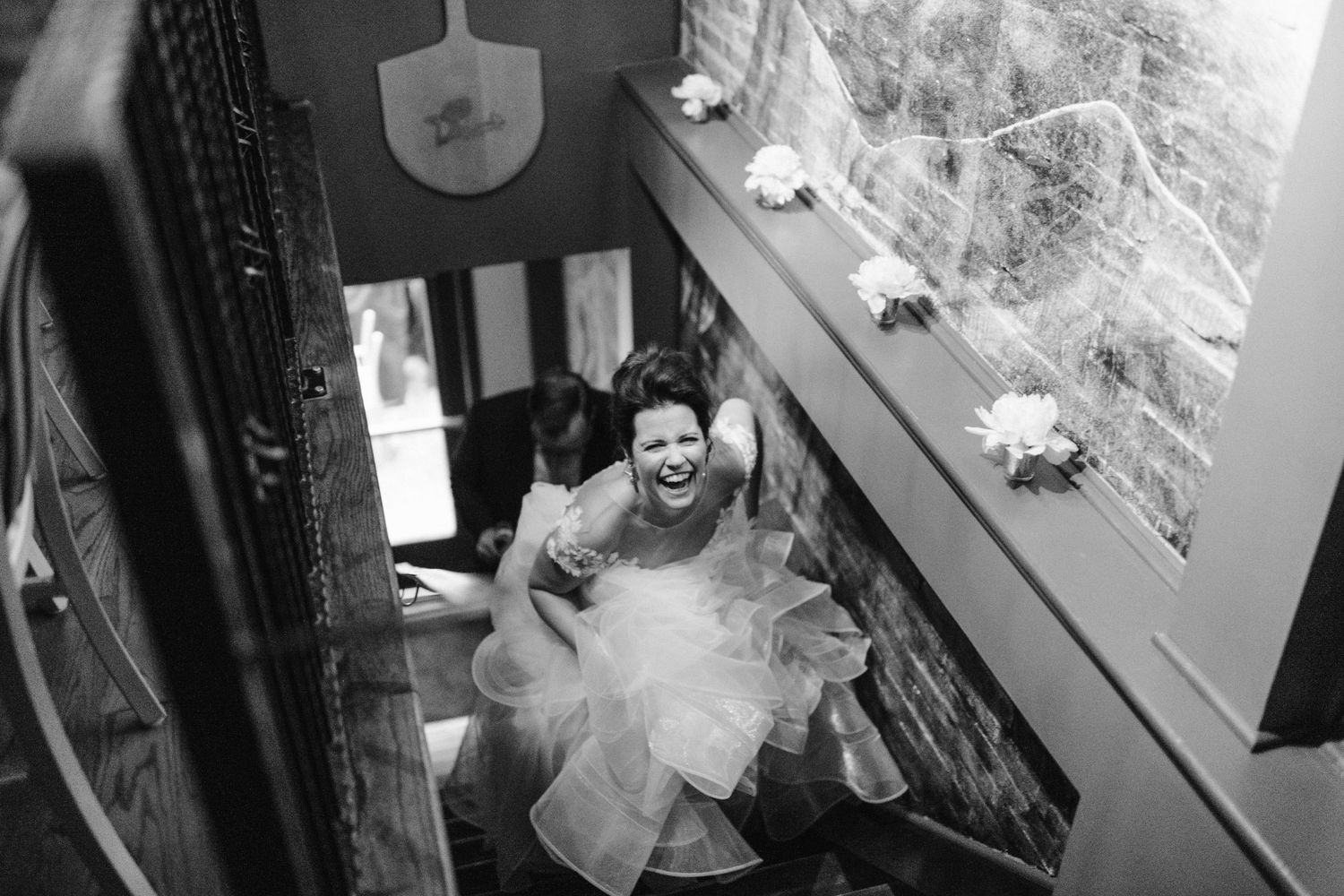 Black and white photo capturing movement on a staircase during a wedding.