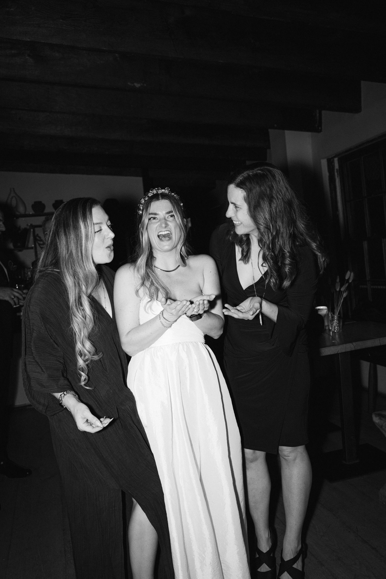 Black and white photo of guests celebrating at a wedding reception with joyful expressions.