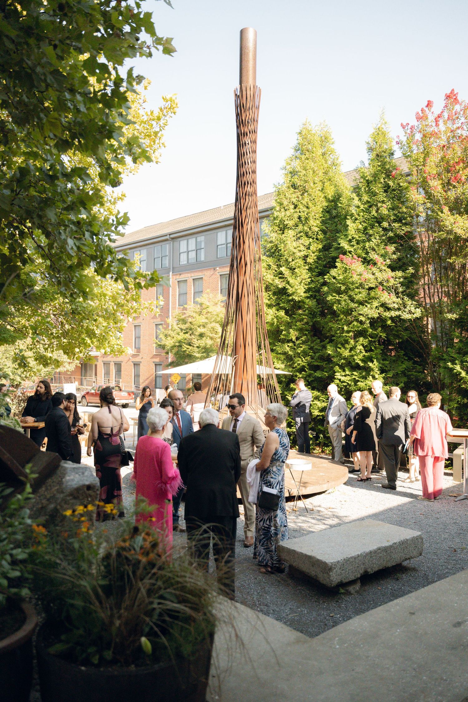 Outdoor wedding reception area with guests mingling under trees.