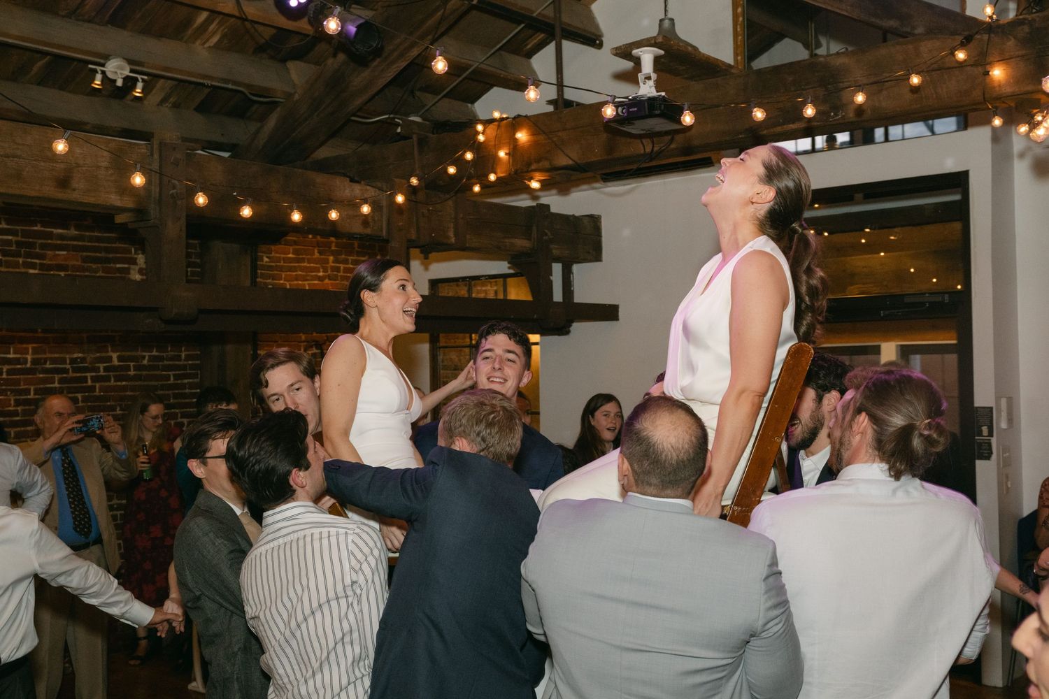 Crowded dance floor at an indoor event with string lights hanging overhead.