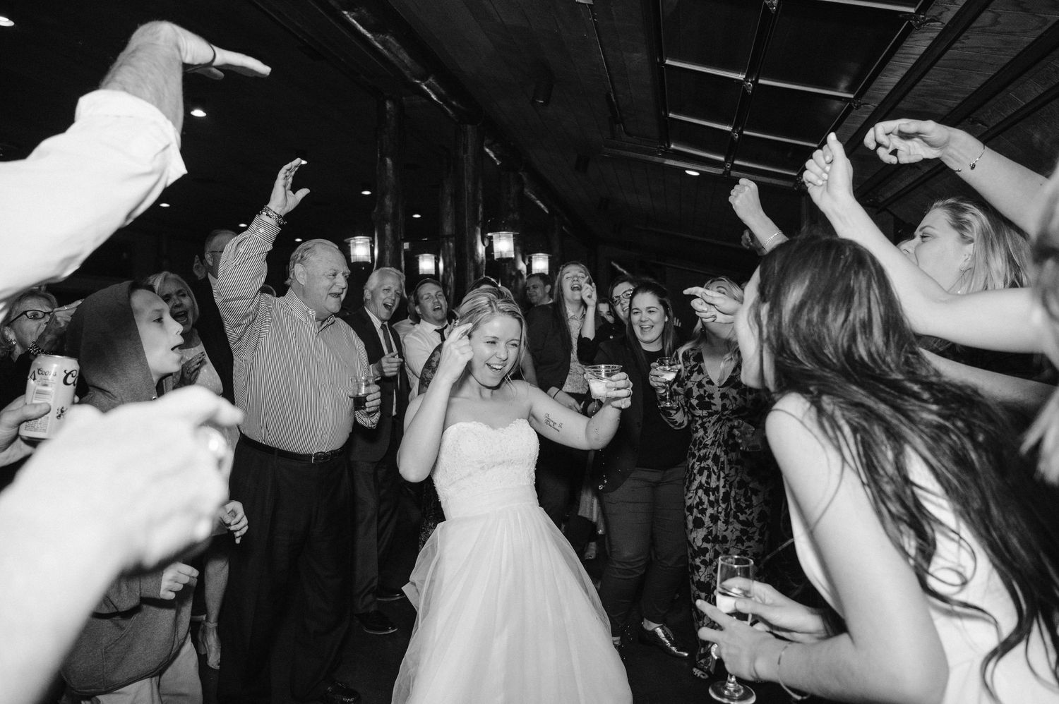 Black and white photo of wedding guests dancing and celebrating with energetic movements.