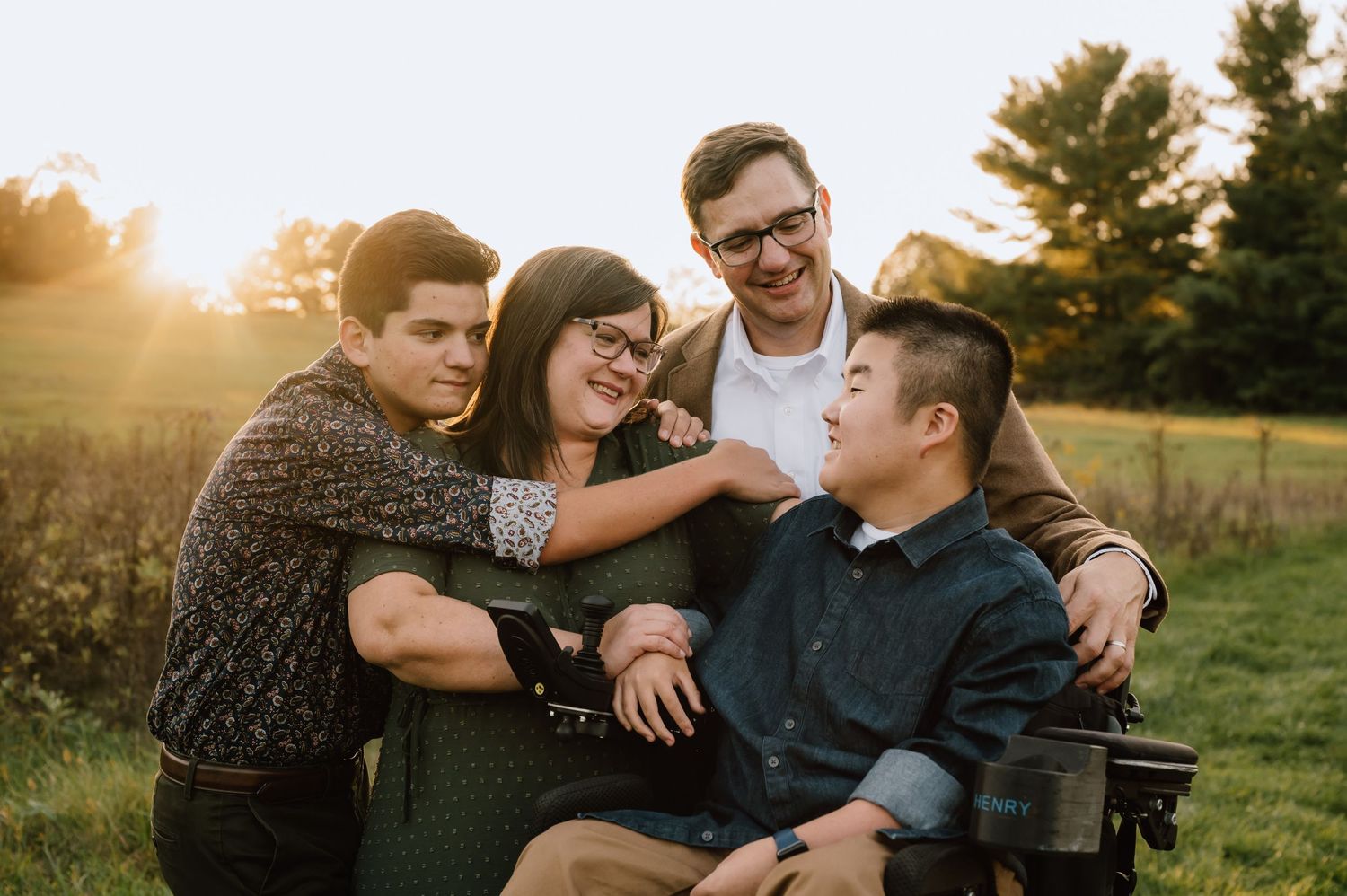 Family enjoying sunset together in a grassy field with warm golden light.