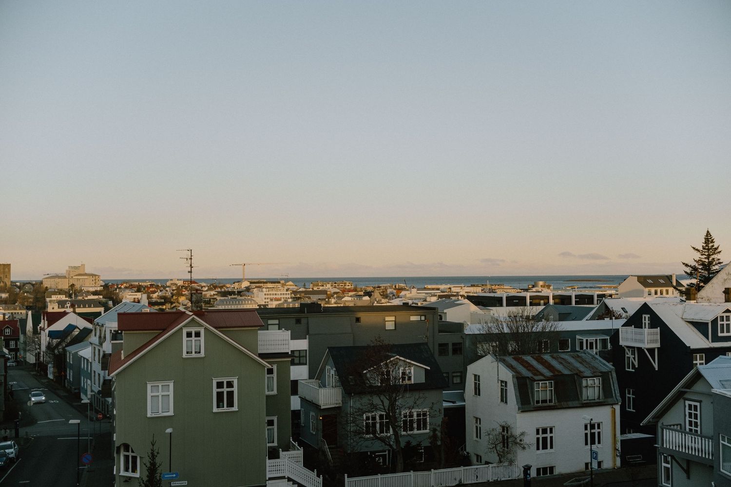 Aerial view of coastal town houses during sunset with harbor in background.