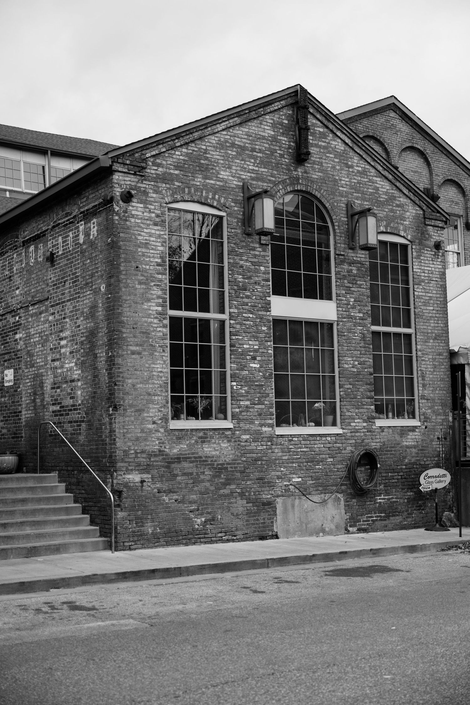A historic brick industrial building with tall arched windows and stone details.