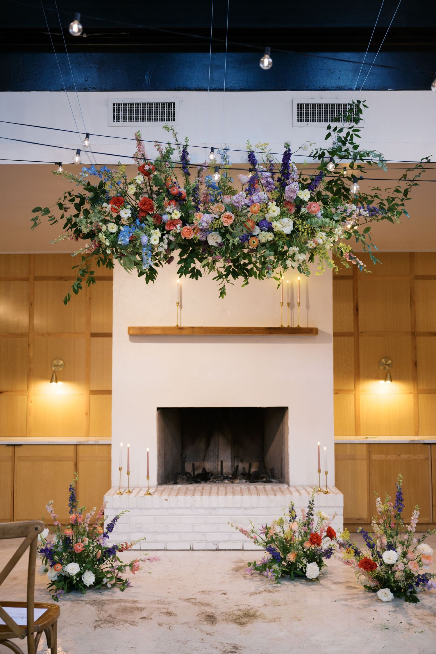An elegant fireplace decorated with suspended floral arrangements and romantic lighting.