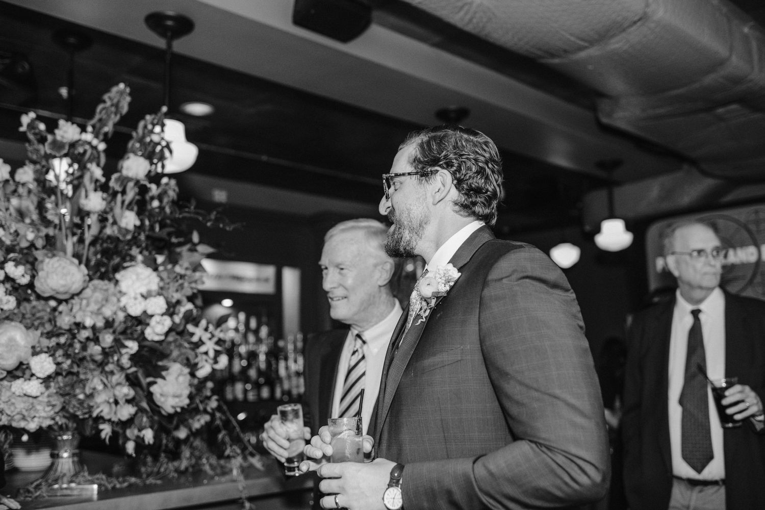 Candid black and white photo of guests enjoying themselves at a wedding reception.