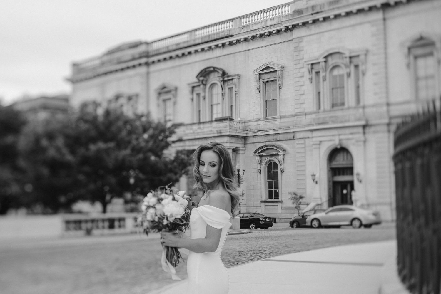 Black and white bridal portrait in front of a grand historic building with ornate windows.