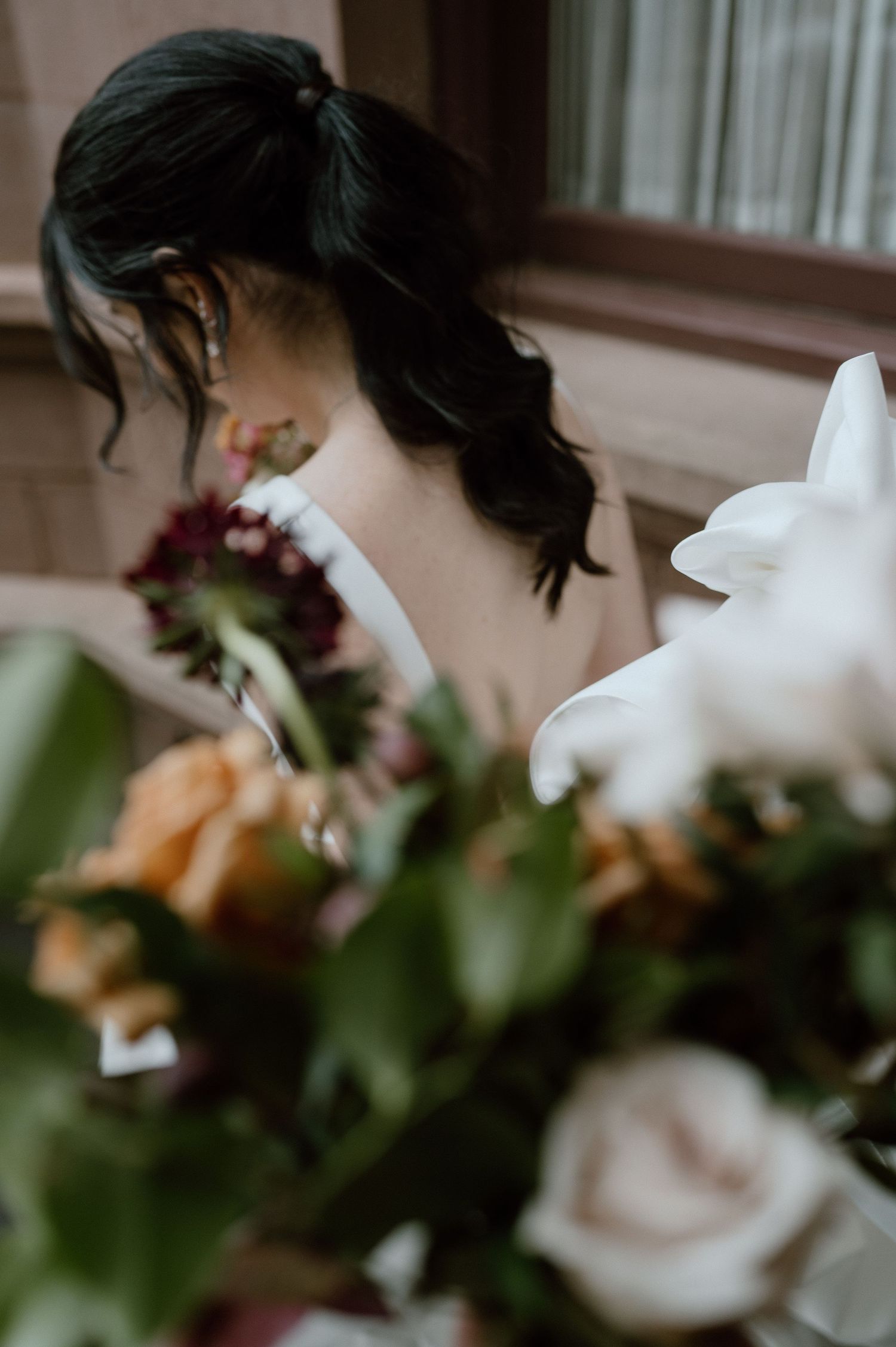 Artistic detail shot of wedding flowers with soft focus on hairstyle.