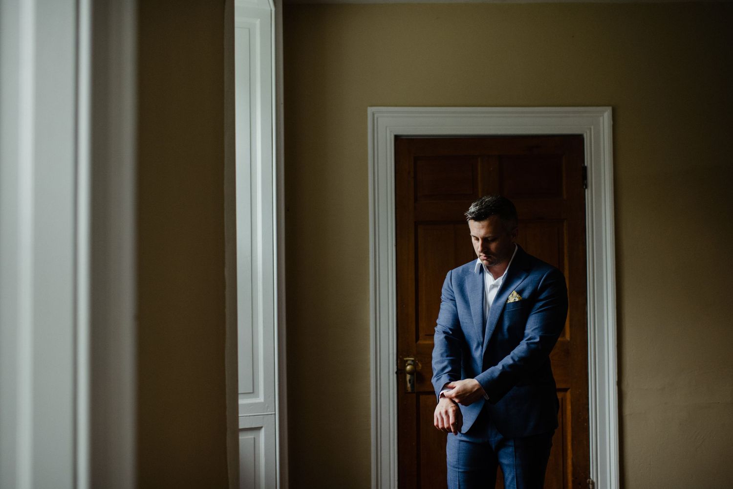 Silhouette of figure in blue suit standing in sunlit doorway.