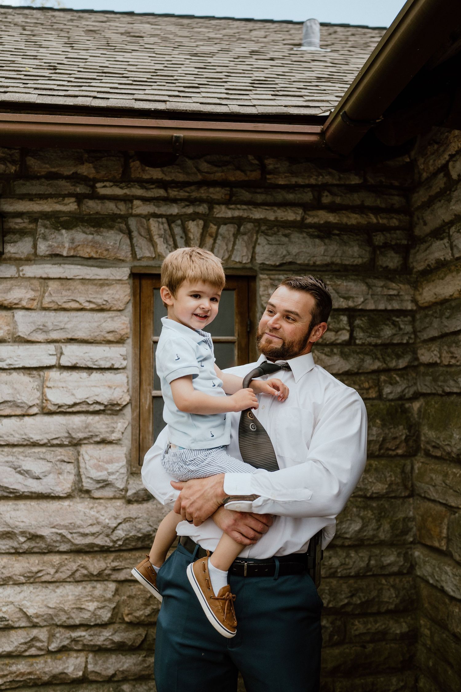 A sweet outdoor portrait against a stone building backdrop in casual attire.