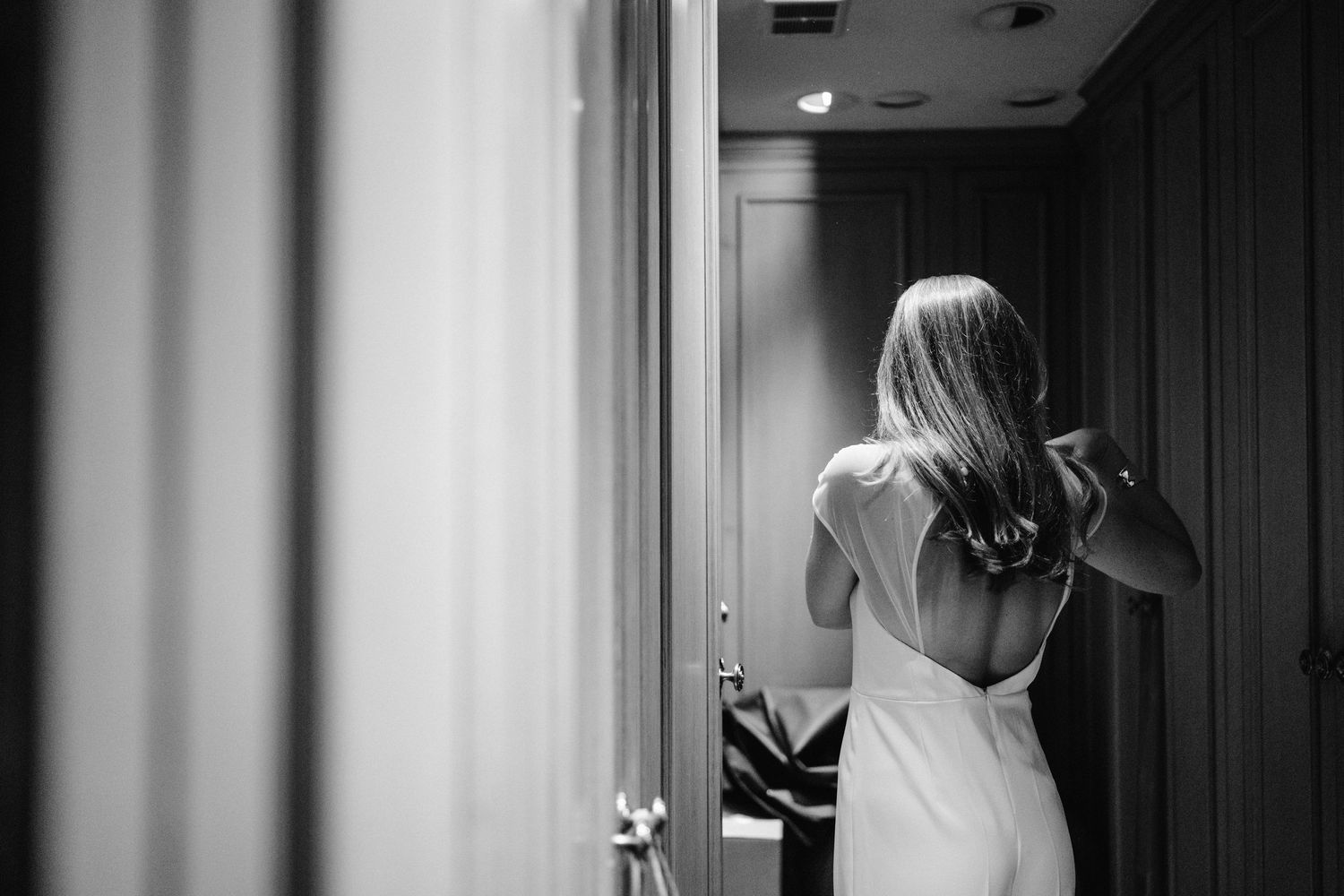 Black and white photo of someone in a white dress viewed from behind.
