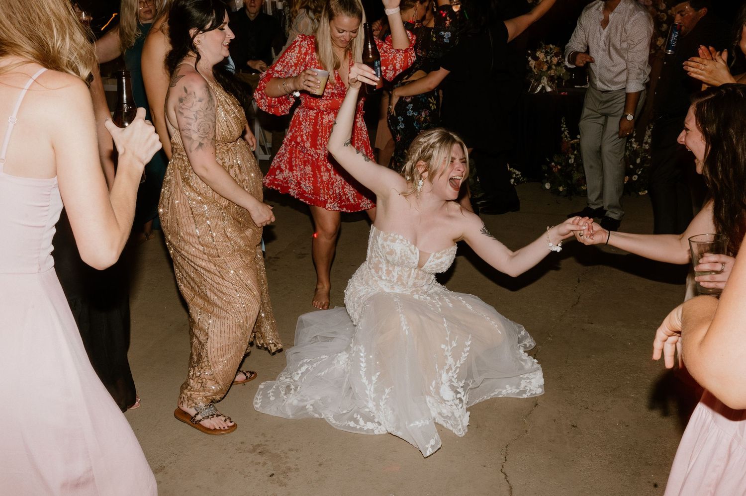 Wedding celebration with guests dancing as bride spins in her white gown on the dance floor.