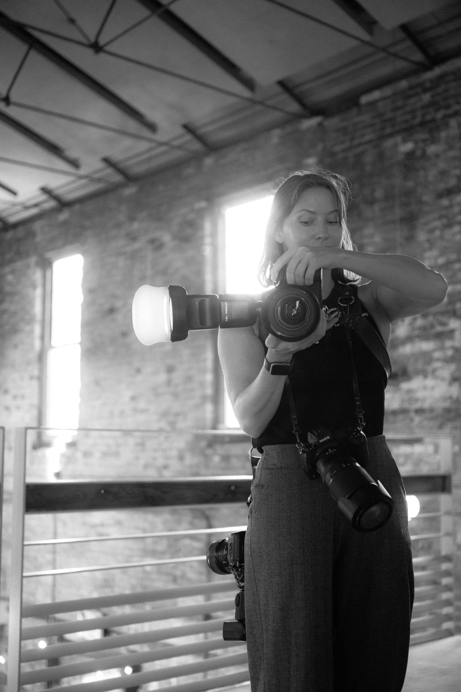 Black and white photos of photographers working in industrial brick space with natural light.
