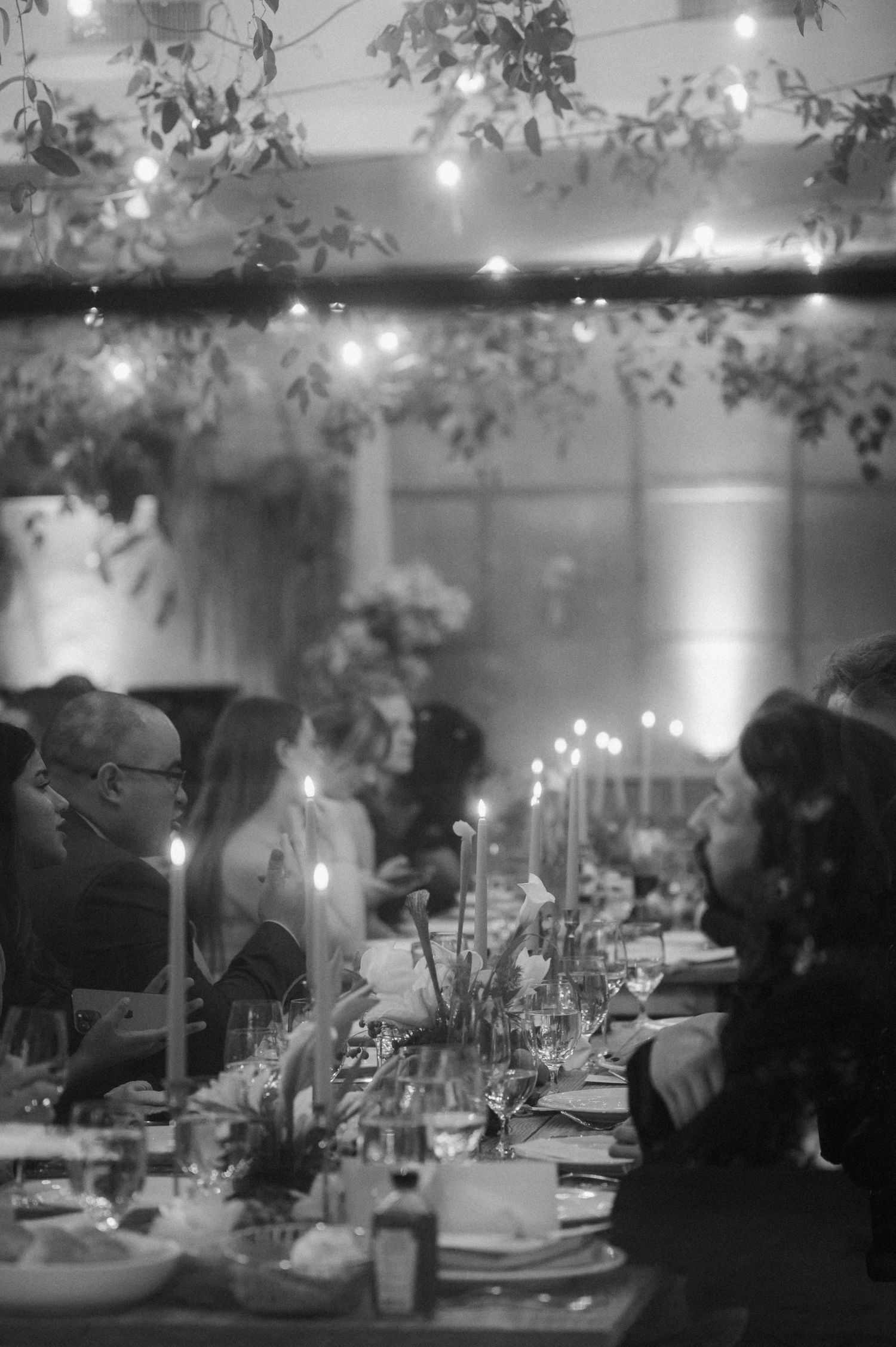 Romantic candlelit reception tables set with glowing tapers and greenery.