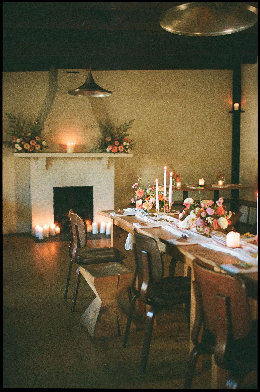 Candlelit wedding reception tables set with elegant place settings in a rustic venue.