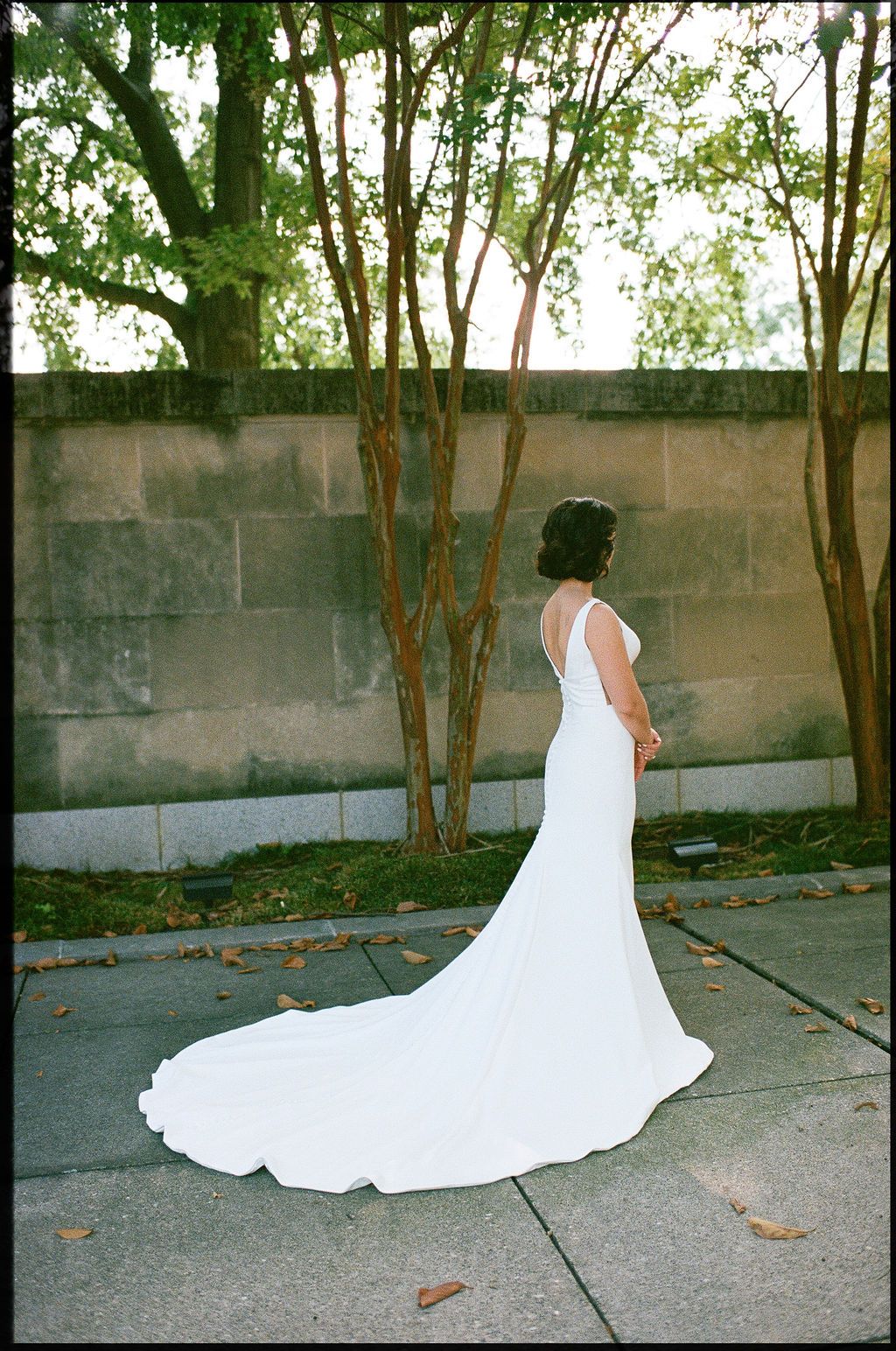 A series of shots showing the flowing train of a white wedding dress against a concrete wall and trees.