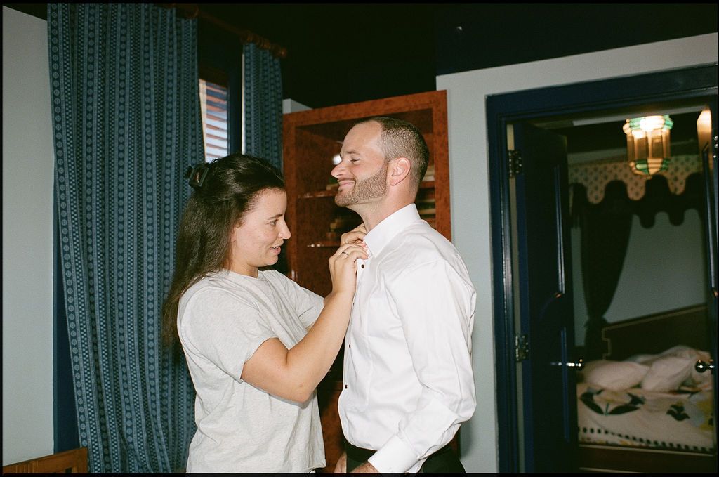 A couple in white shirts share an intimate moment while dancing together in a dimly lit room.
