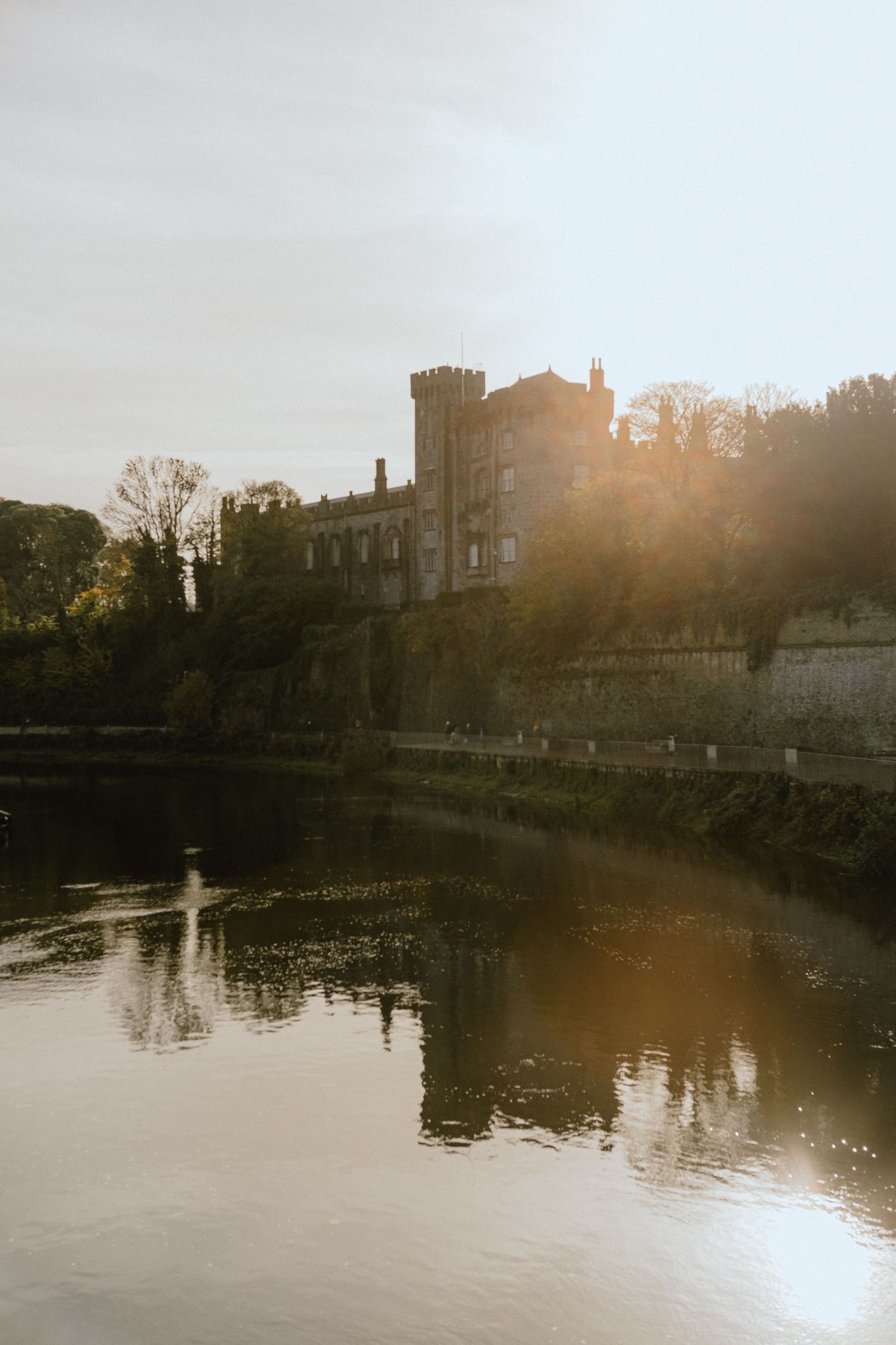 Medieval castle reflected in still waters at sunset with stone walls.