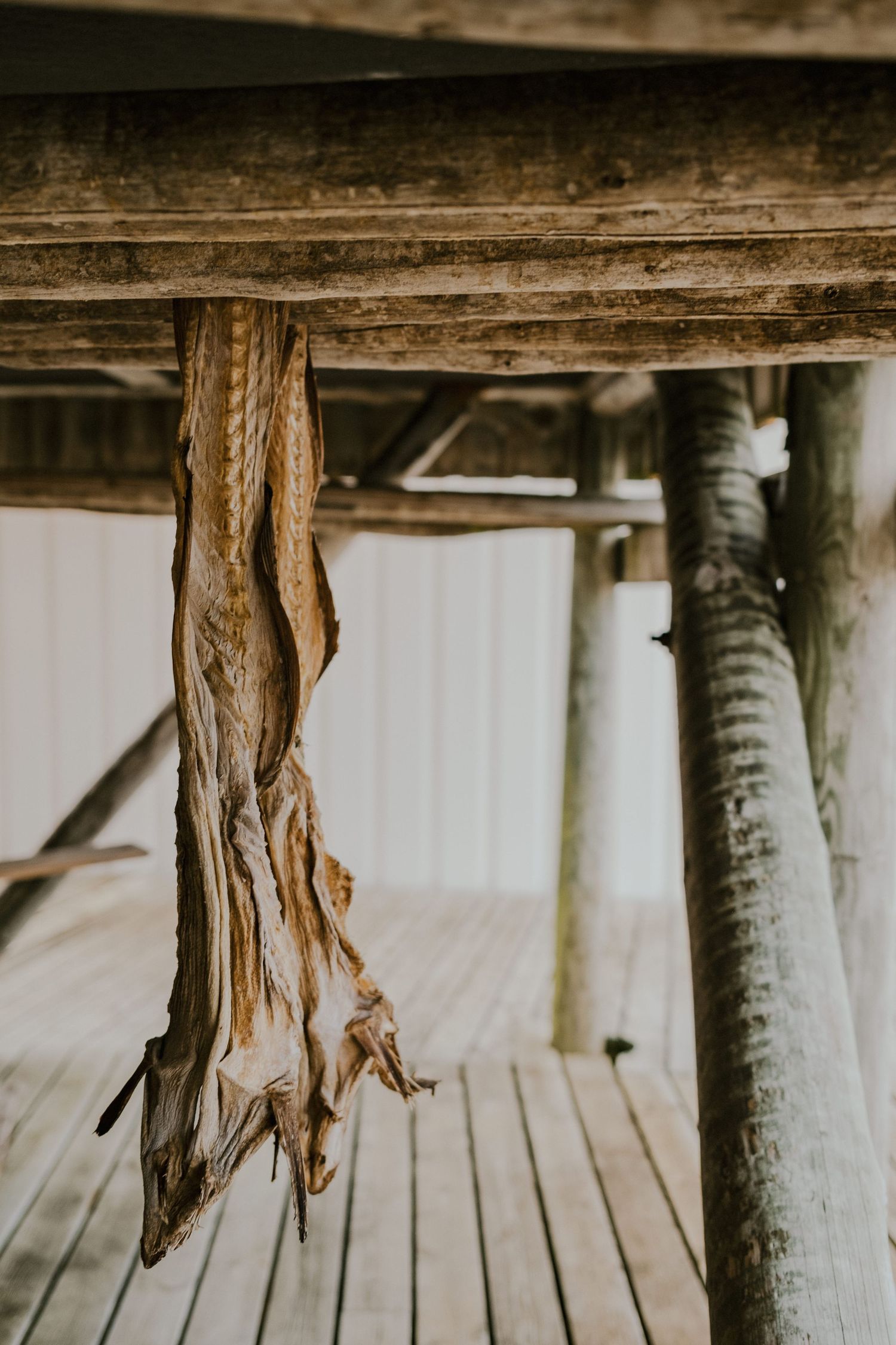 Close-up of weathered wooden rope or fabric hanging from rustic timber beam on wooden deck.