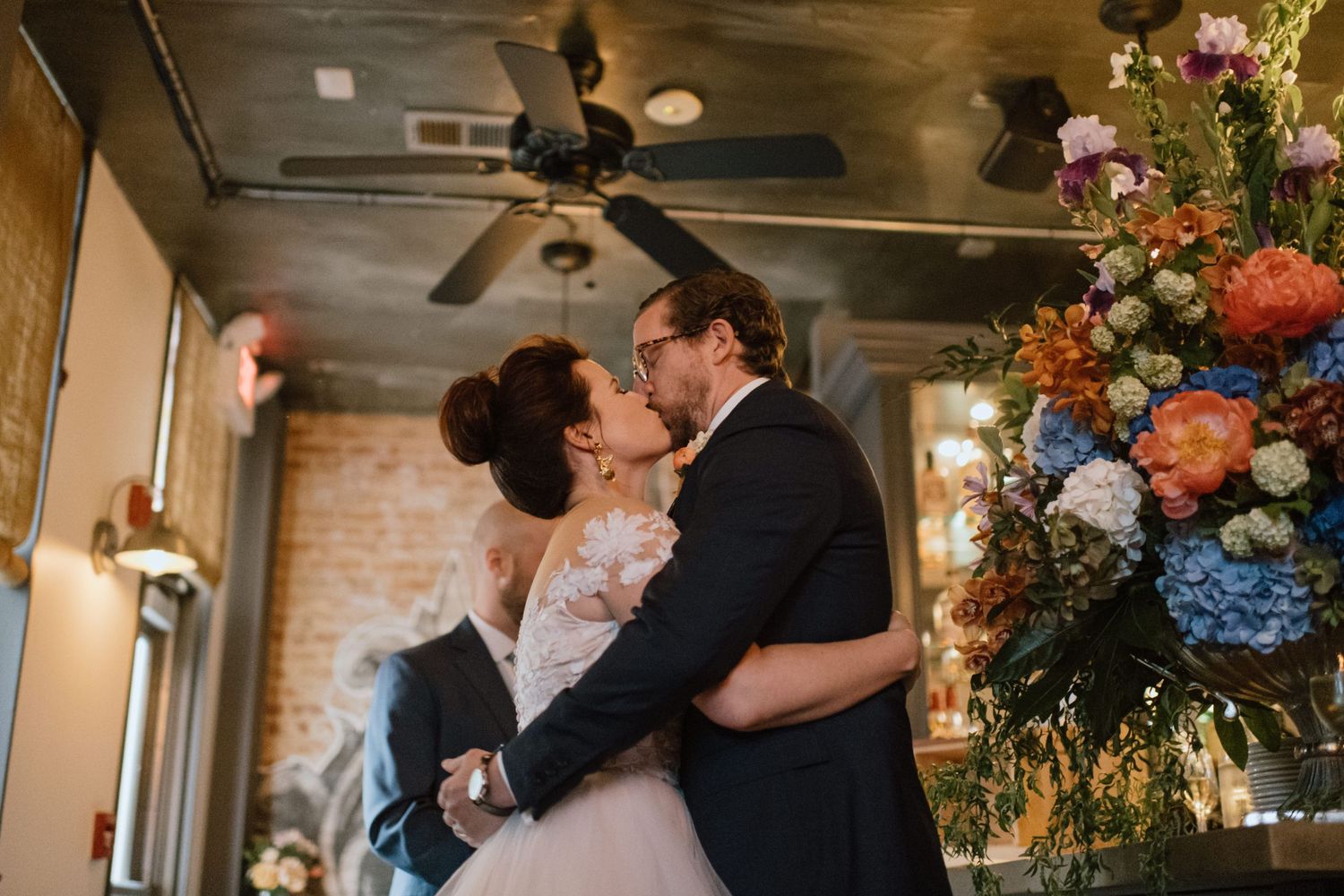 A romantic kiss shared during a wedding ceremony with beautiful floral decorations.