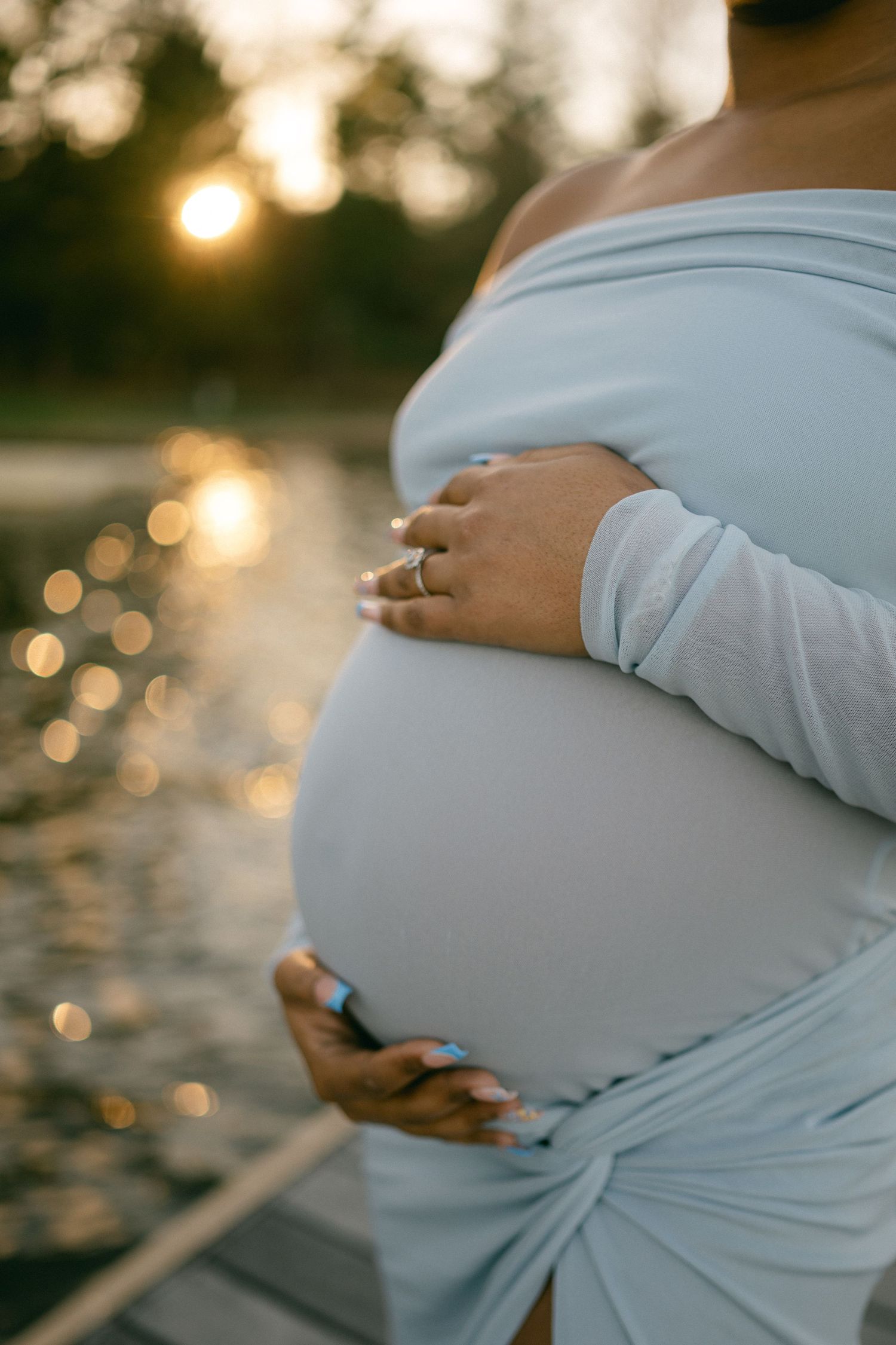 close up pregnant woman baby bump water glistening in background