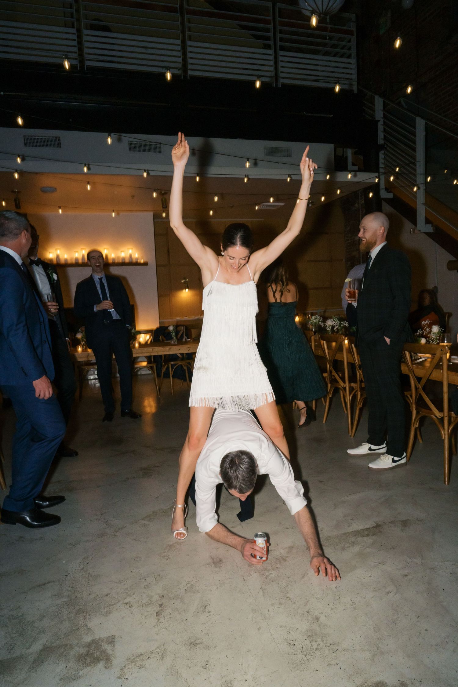 Fun dancing moment at a wedding reception where someone performs an acrobatic move on the dance floor.