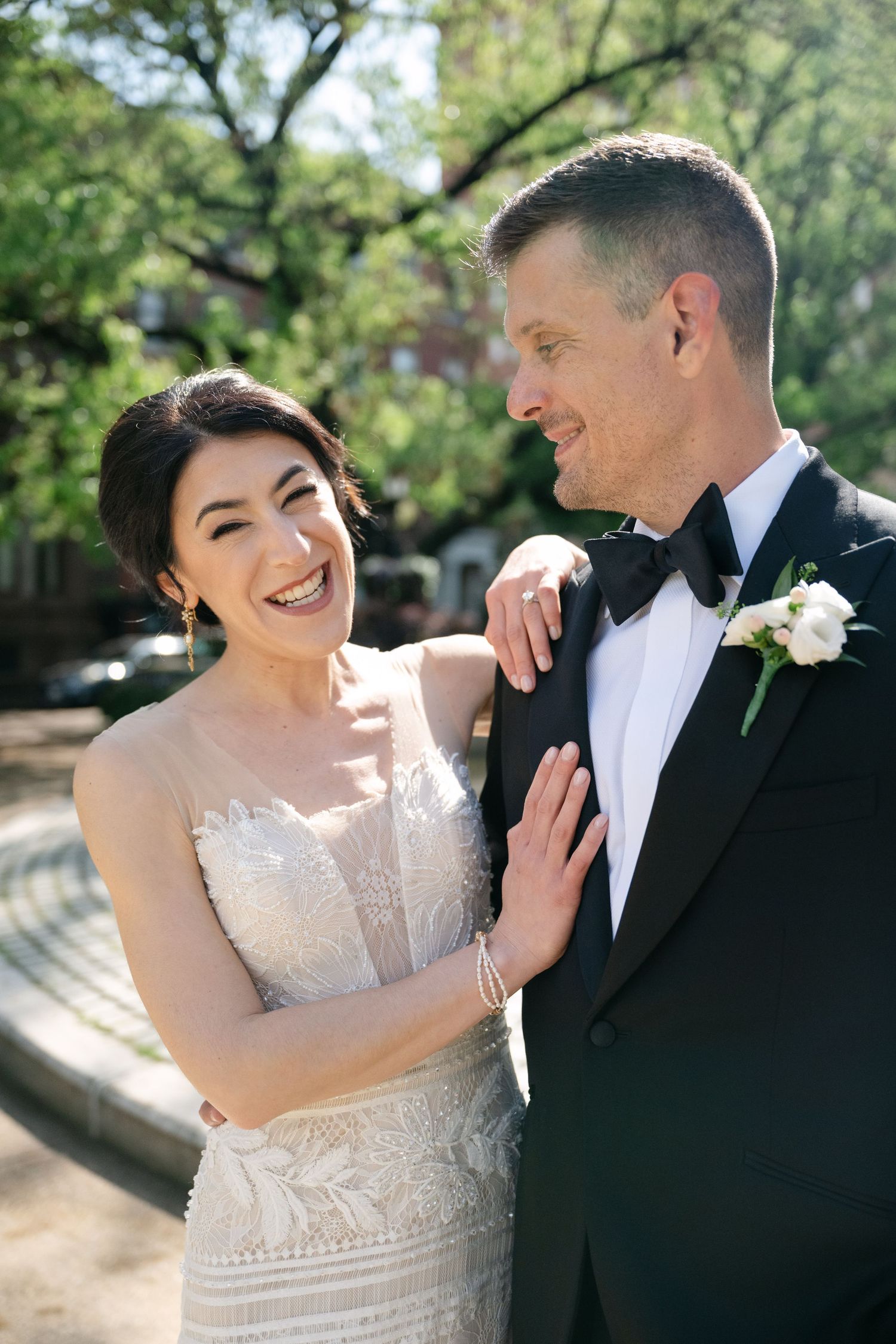 A joyful wedding couple sharing a candid moment in their formal attire outdoors.