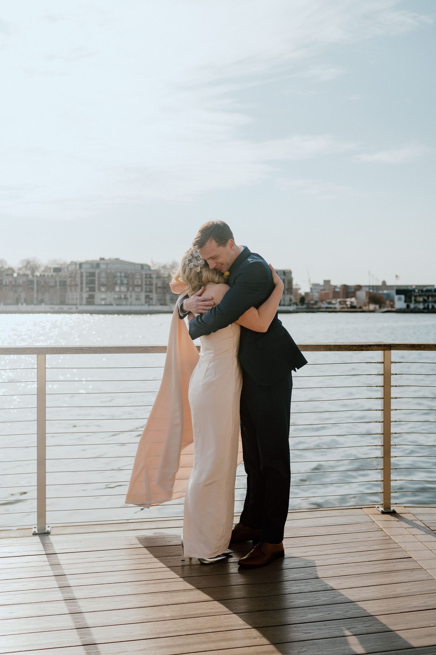 Romantic embrace between couple on wooden pier with water view.