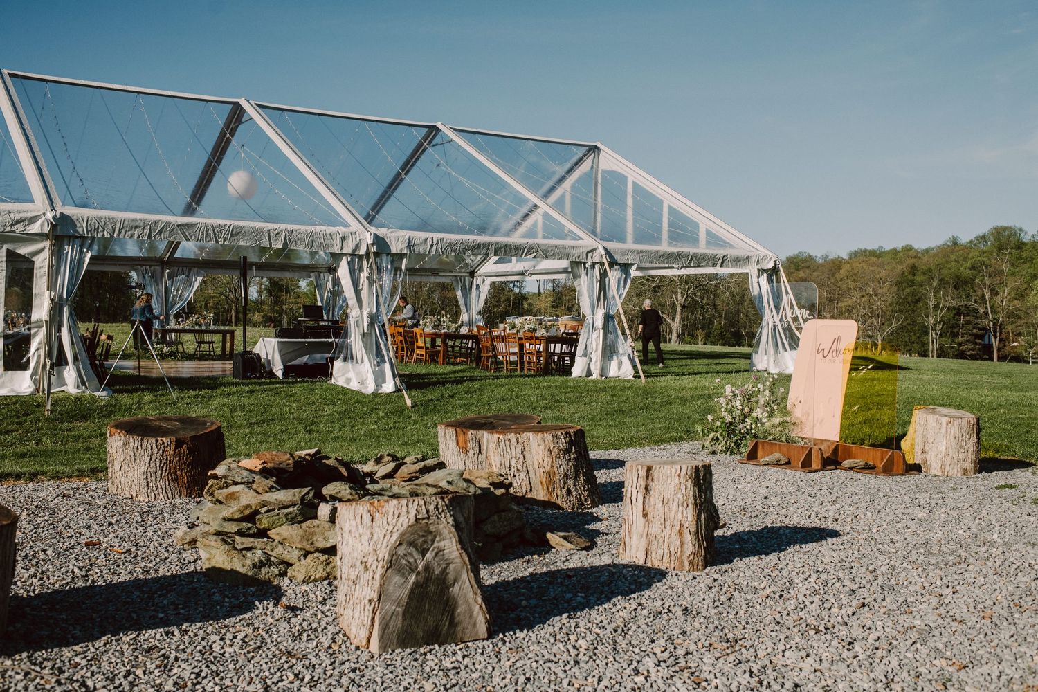 Clear tent reception area with rustic wooden stump seating arranged in a circle.
