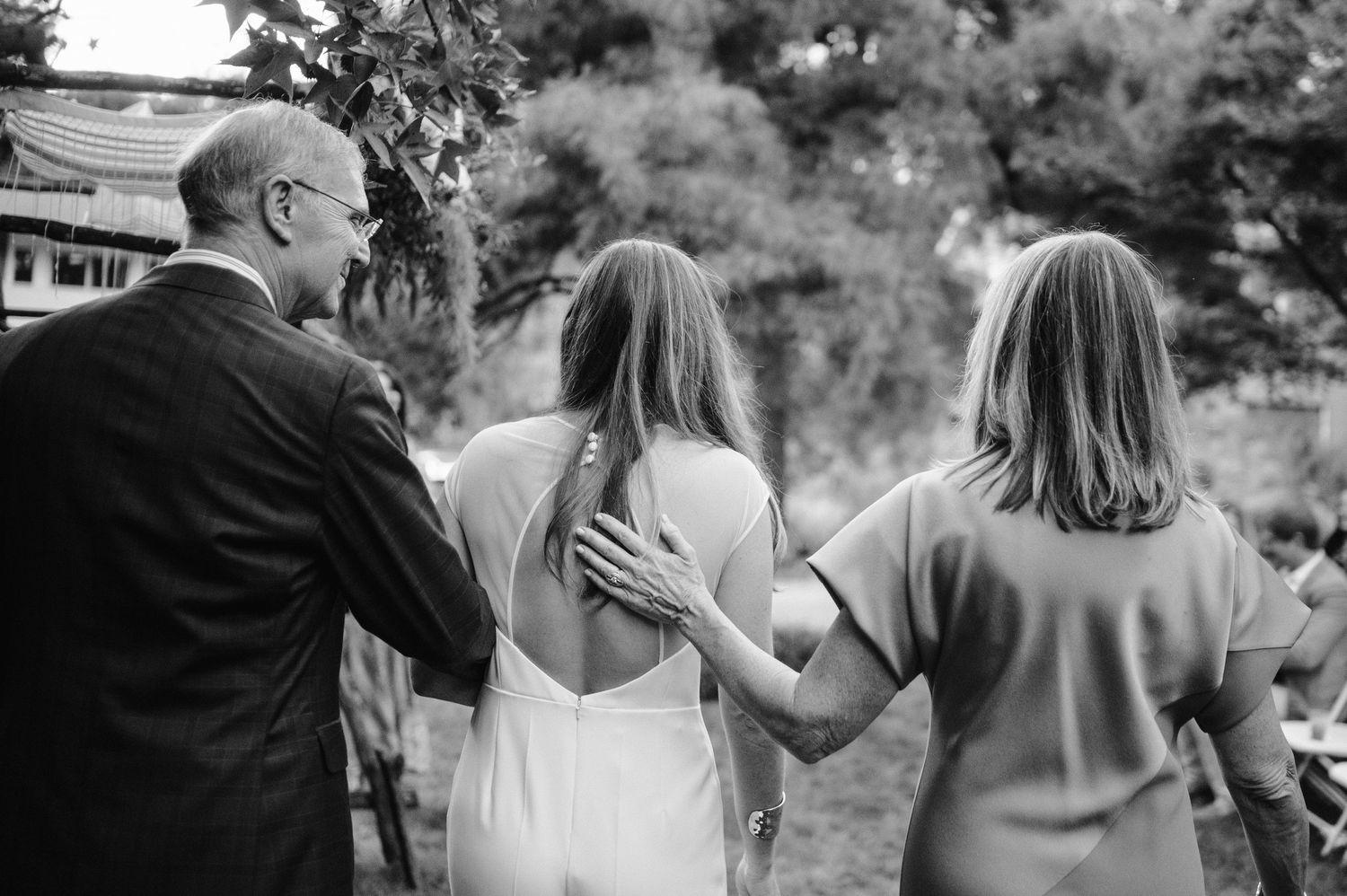 Black and white photo of wedding attendees walking together during an outdoor celebration.