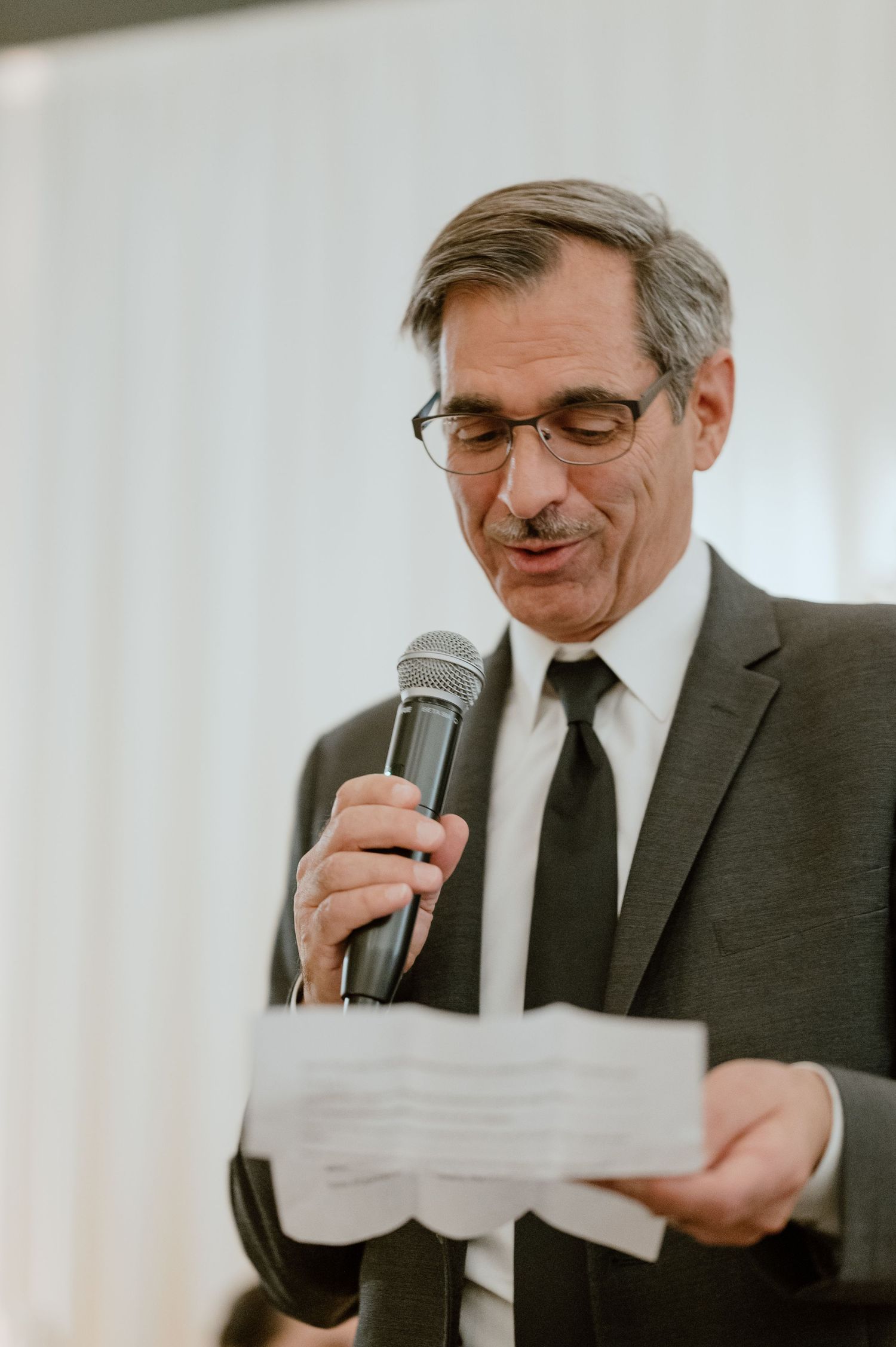 Speaker delivers speech while reading from paper at formal event.