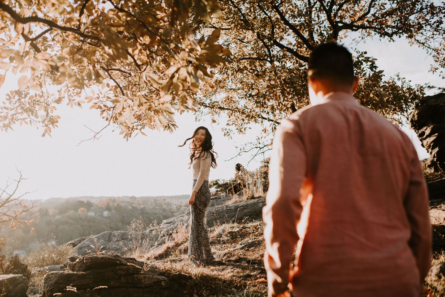 Golden sunlight bathes couple during romantic mountain overlook photoshoot.