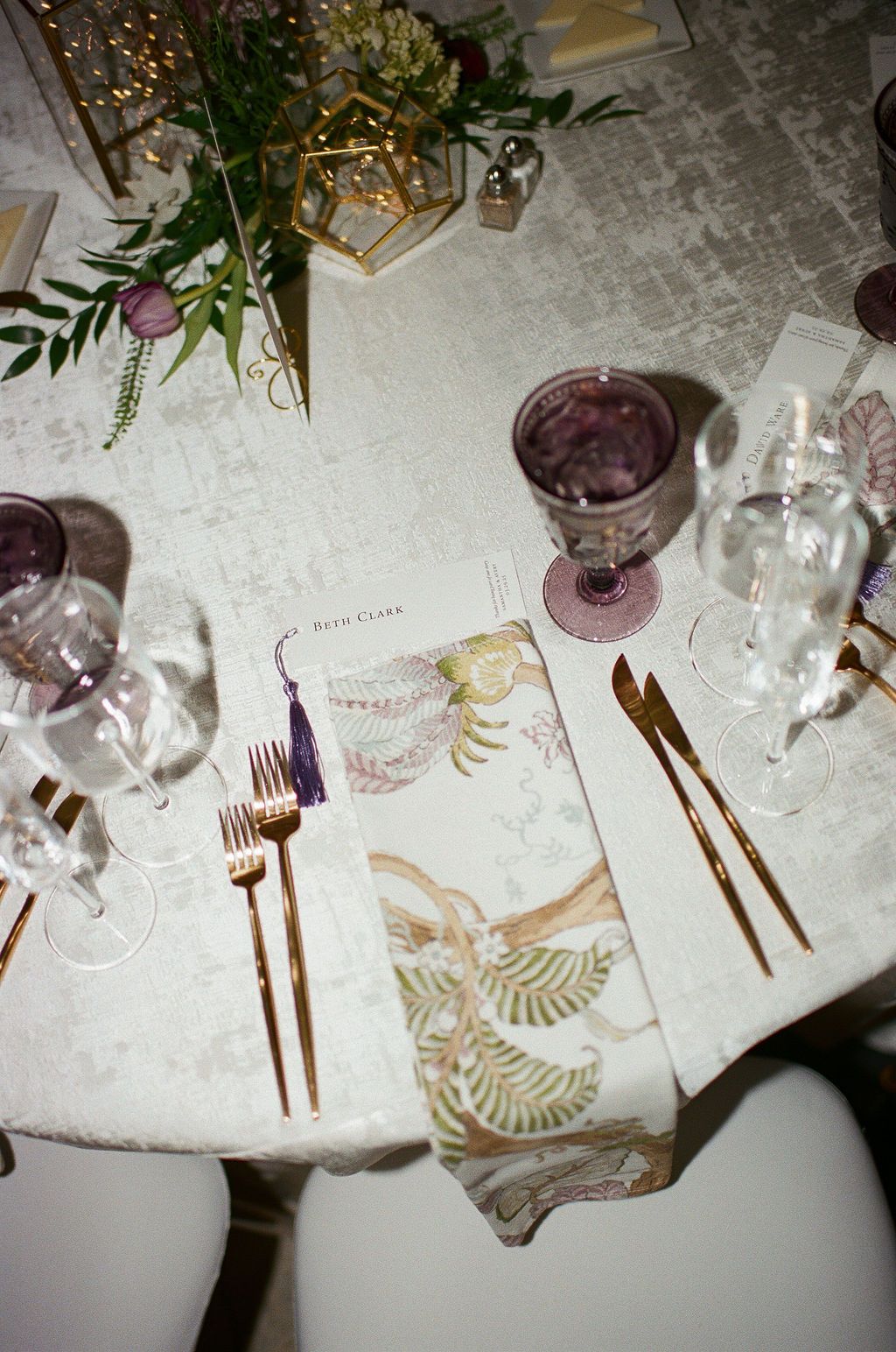 Elegant place setting with purple glassware, gold cutlery and patterned napkins at George Peabody Library Wedding in Baltimore