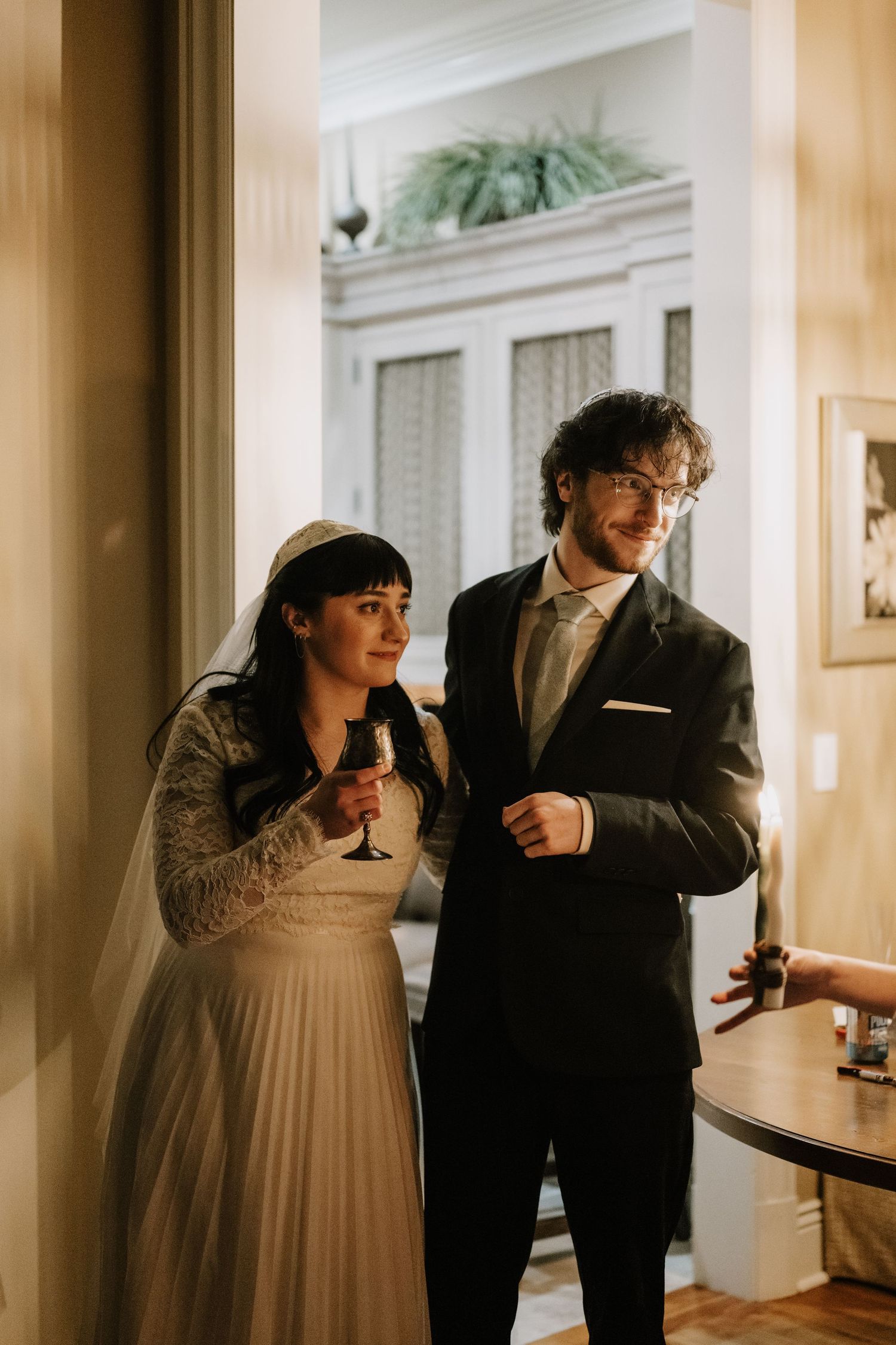 Couple walking through an elegant hallway with cream colored walls.