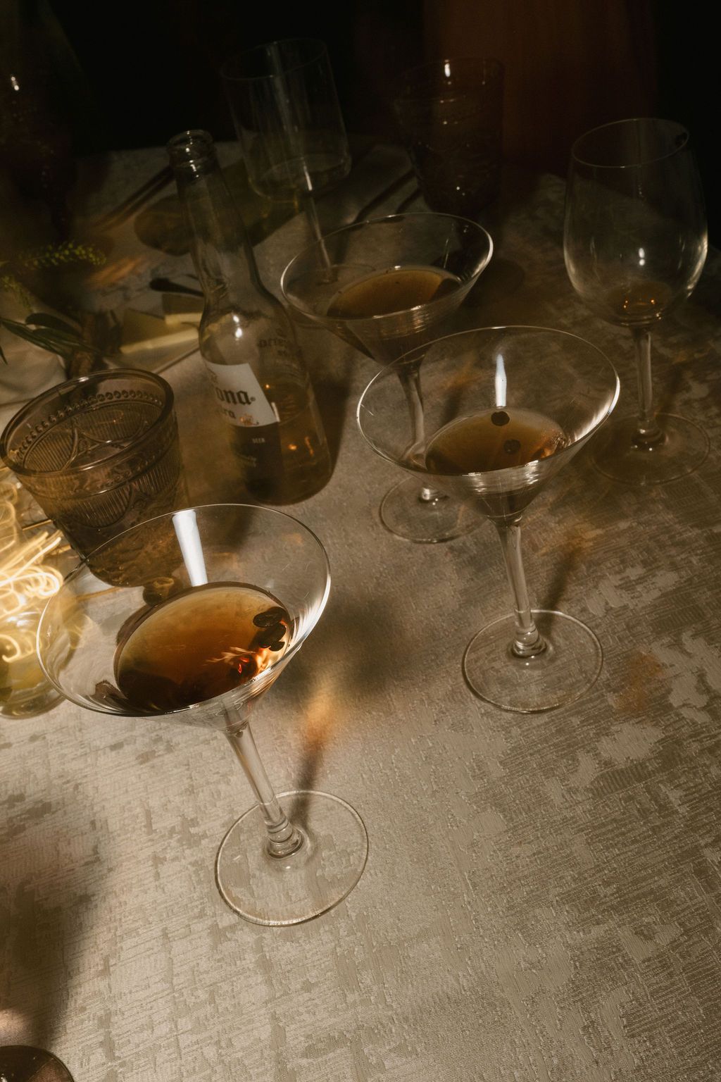 Multiple wine glasses arranged on a textured surface in dim lighting.