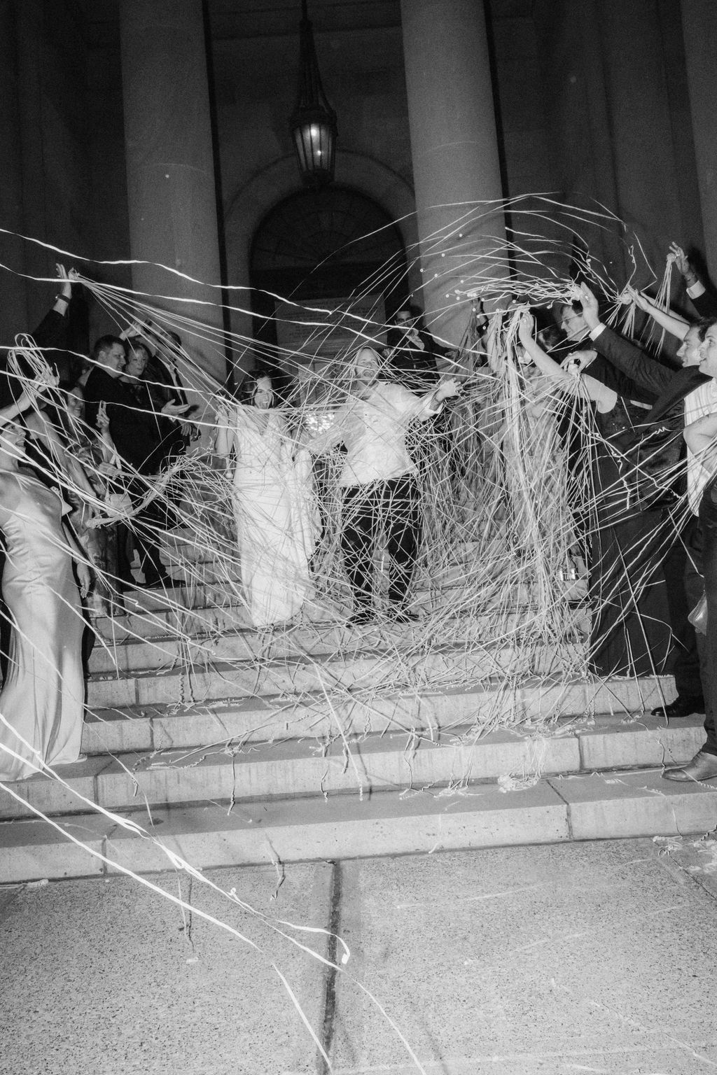 Black and white photograph showing a long exposure of streaking lights and movement across a concrete surface at night.