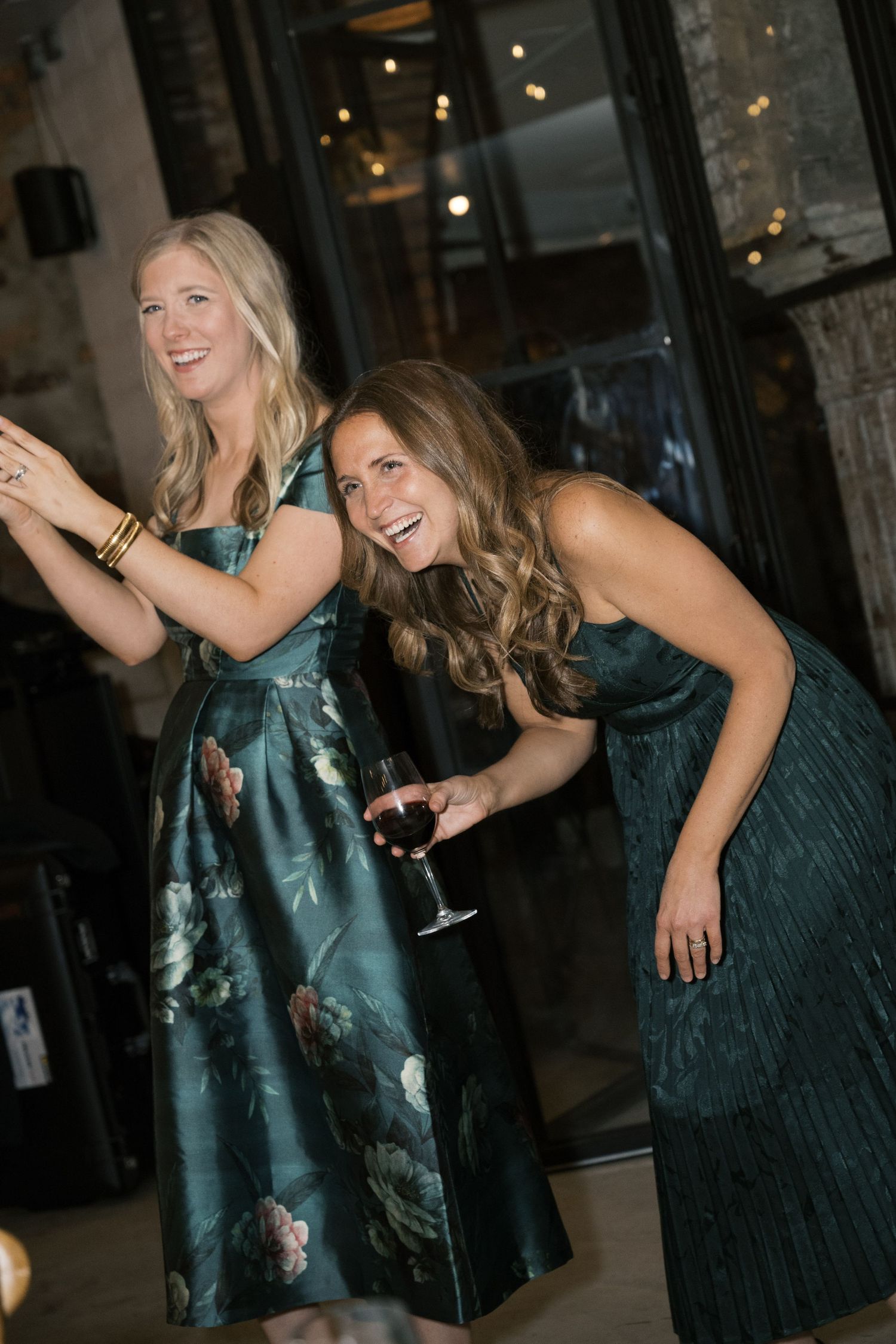 Two guests in elegant teal dresses enjoying themselves at an evening party.