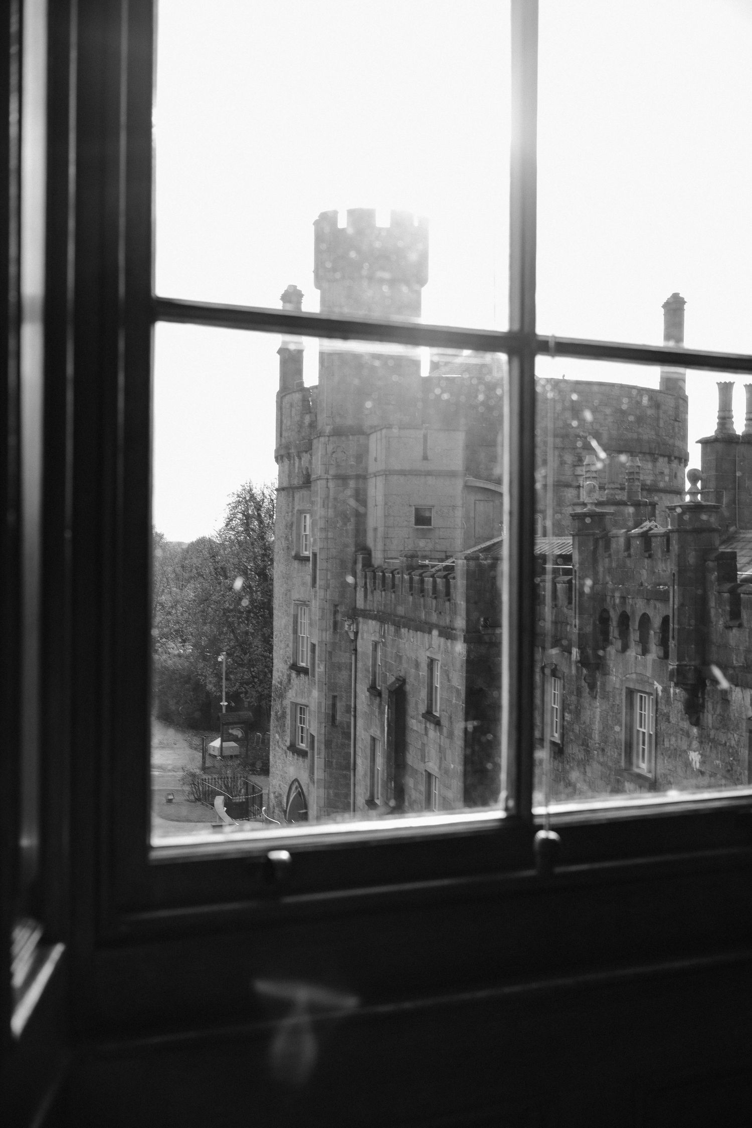View of a gothic castle through a historic window frame in black and white.
