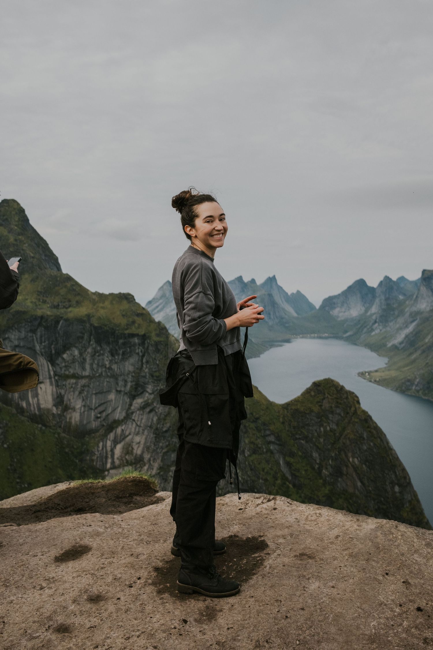 Hiker enjoying panoramic mountain views at Reinebringen viewpoint in Lofoten, Norway.