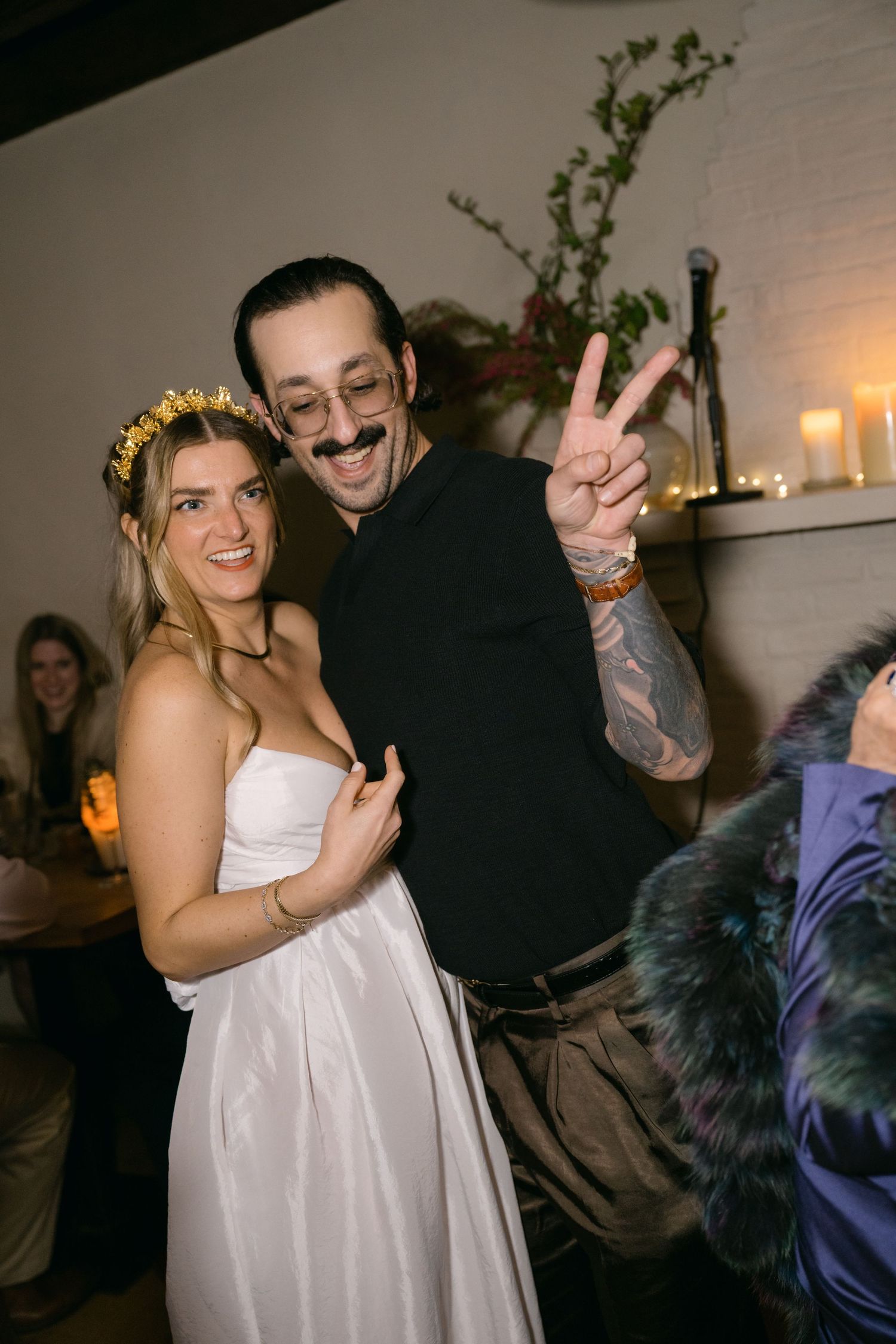 Two people posing together at a wedding celebration with decorative lighting and floral arrangements at Fadensonnen in Baltimore